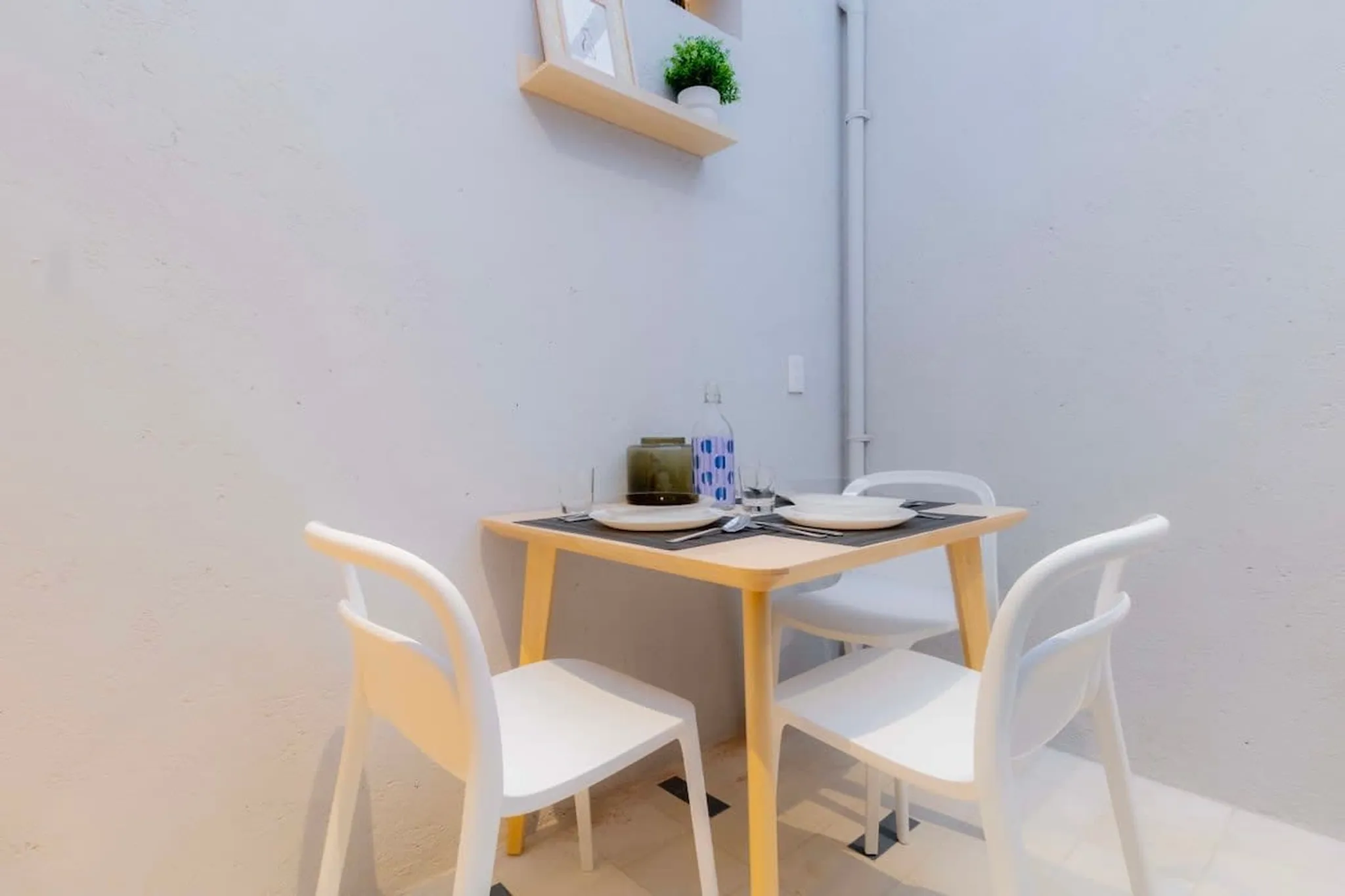 A close-up of a small dining table set with two plates, cutlery, and glasses.