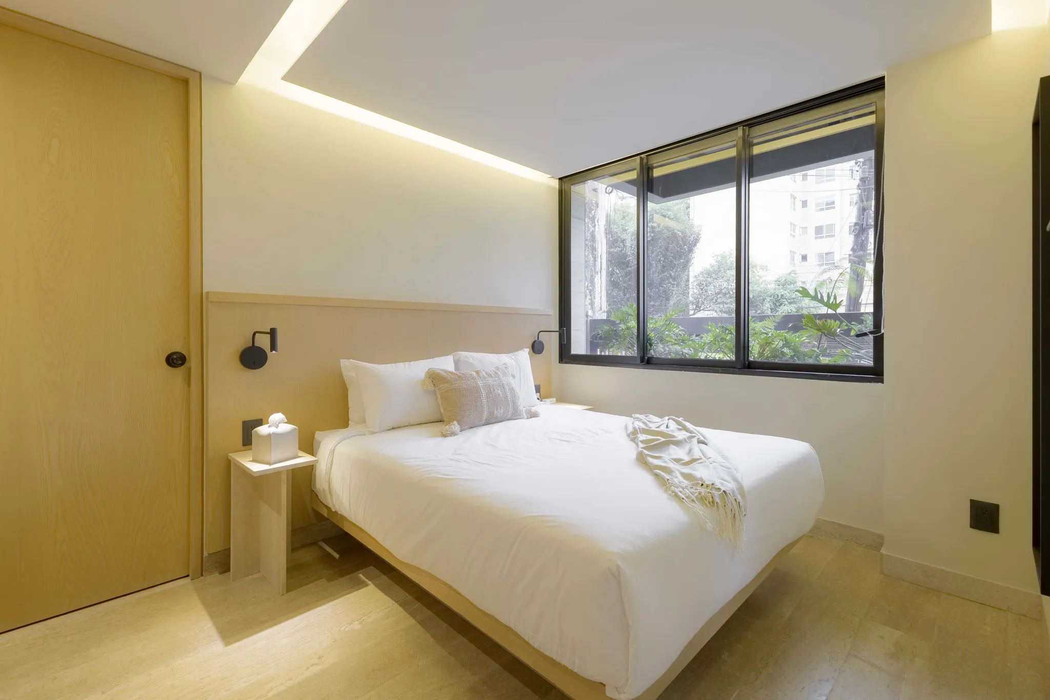 A modern bedroom with a bed, a bedside table, and a door.