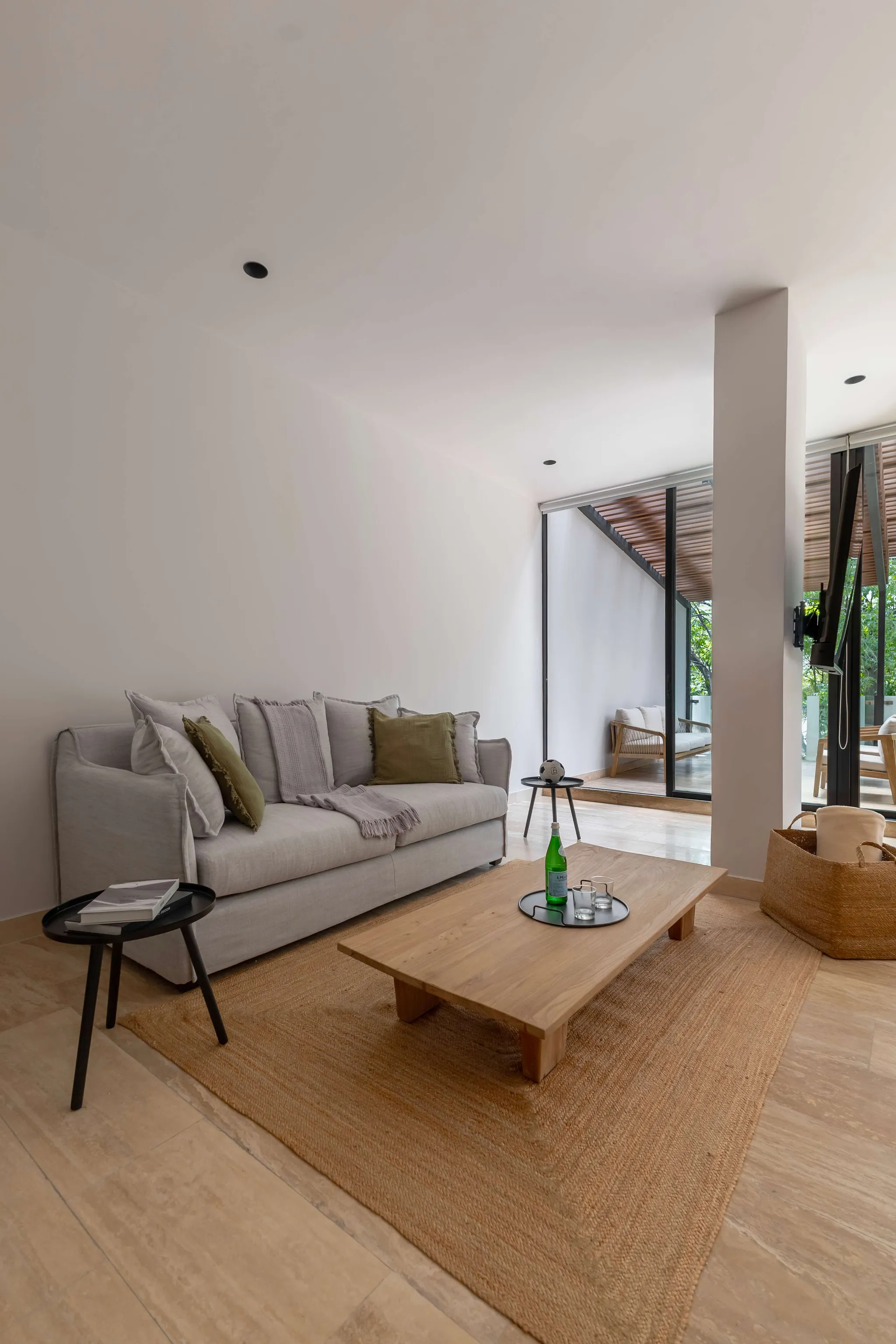 A bright living room with a light gray couch, wooden coffee table, and a woven rug.