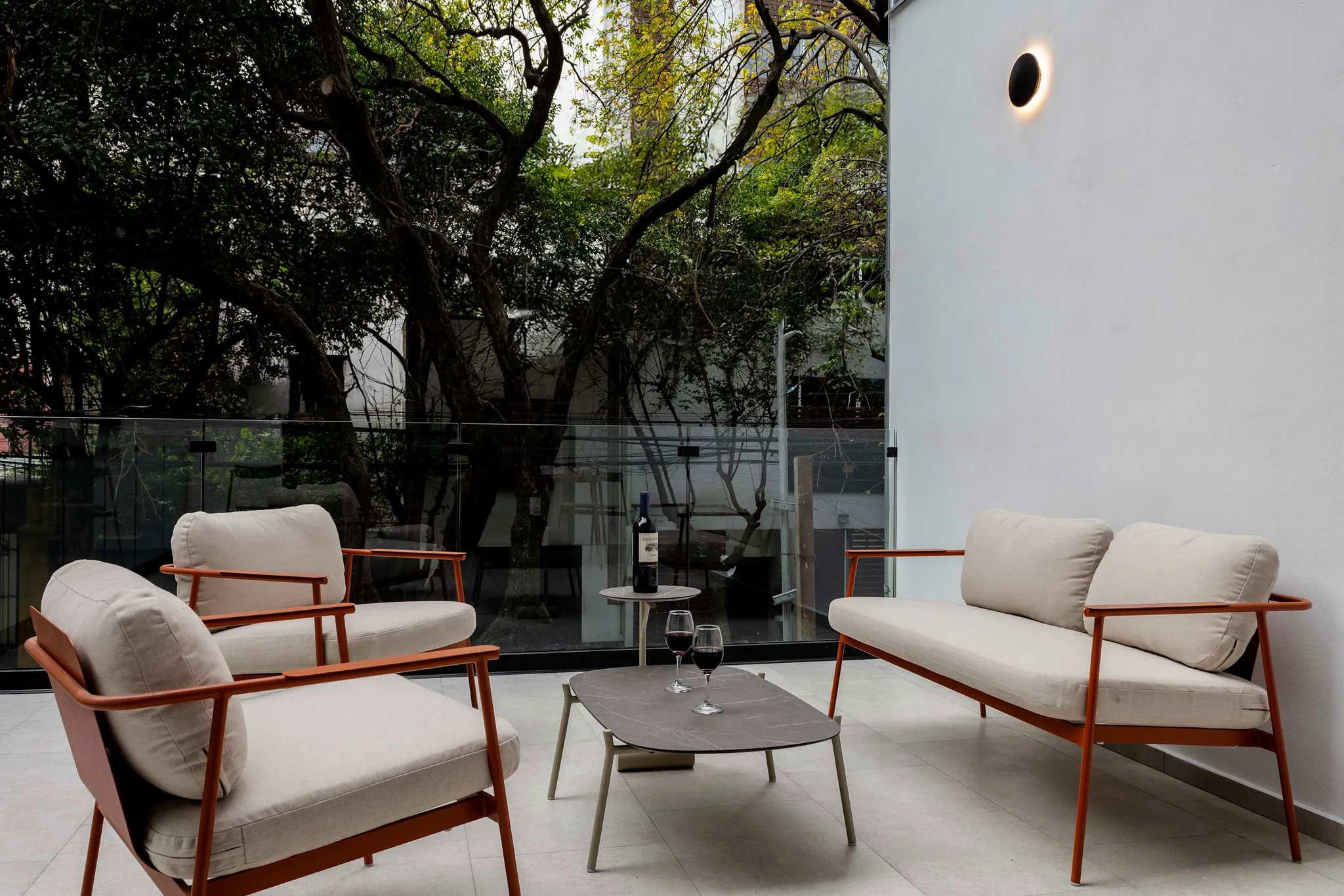A modern outdoor seating area with chairs, sofa, coffee table, and wine.