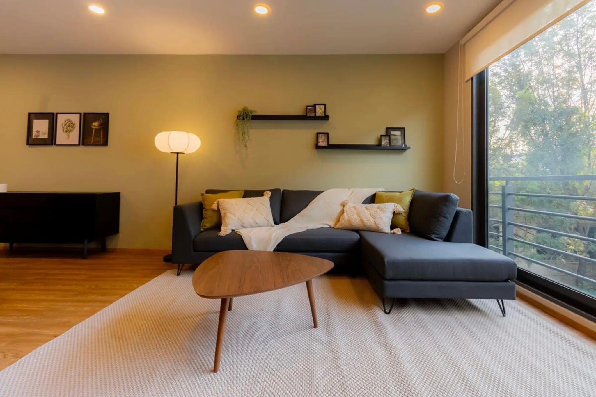 A grey sectional sofa with pillows and a throw blanket sits on a rug in a room.