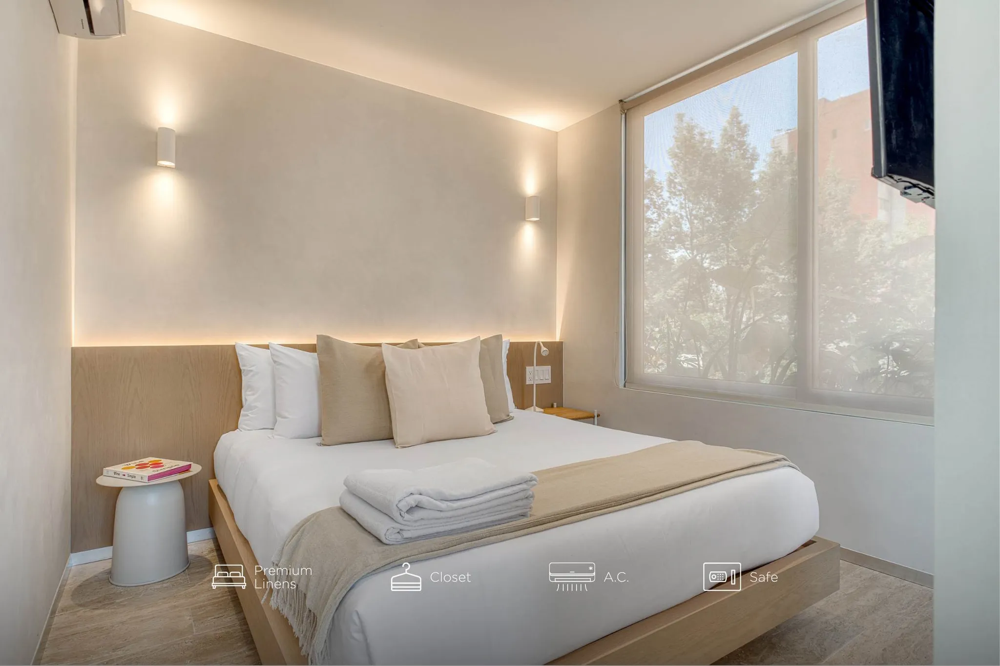 A hotel room with a bed, nightstand, and a large window.