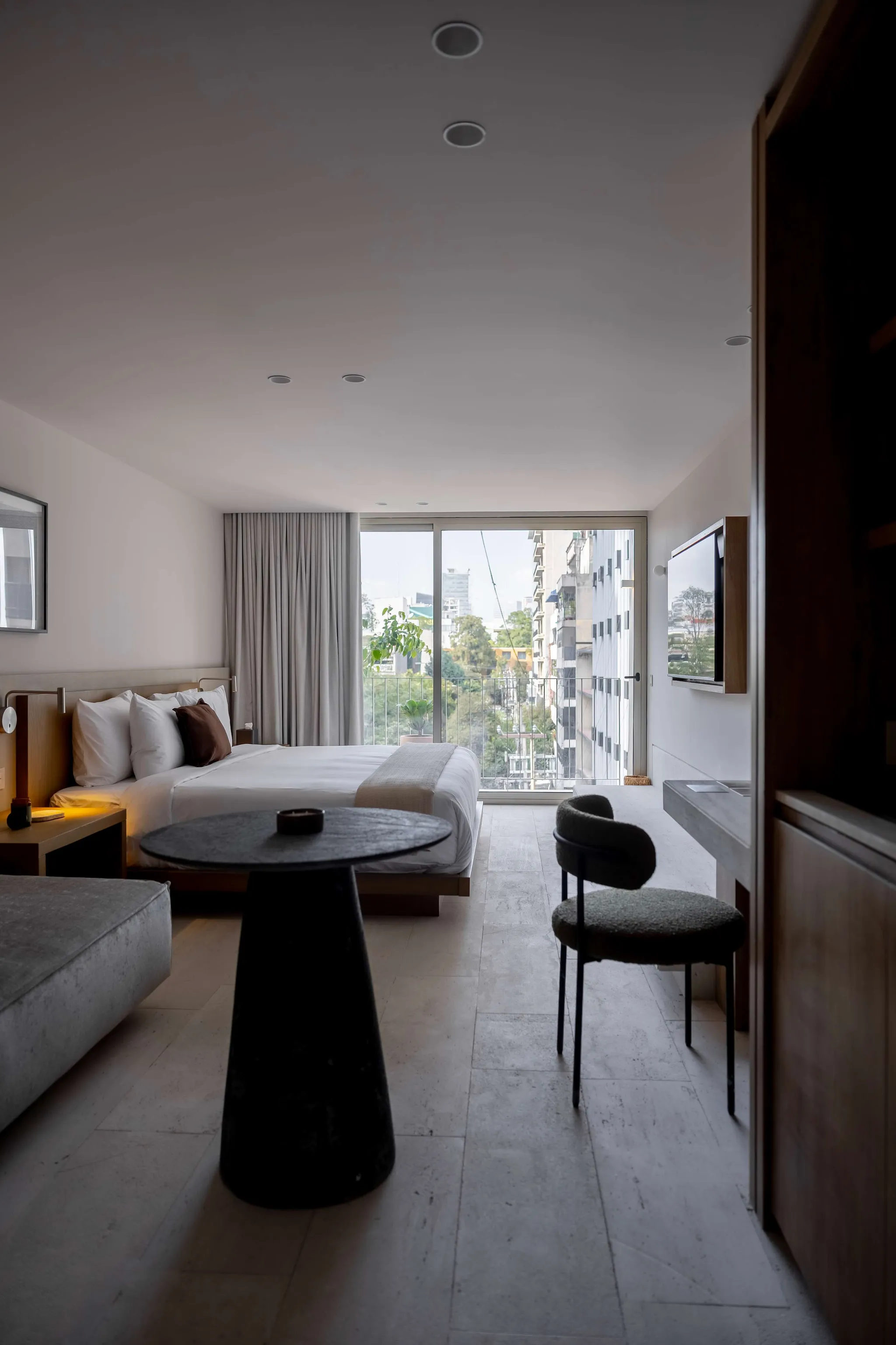 A well-lit hotel room with a bed, a table and a chair.