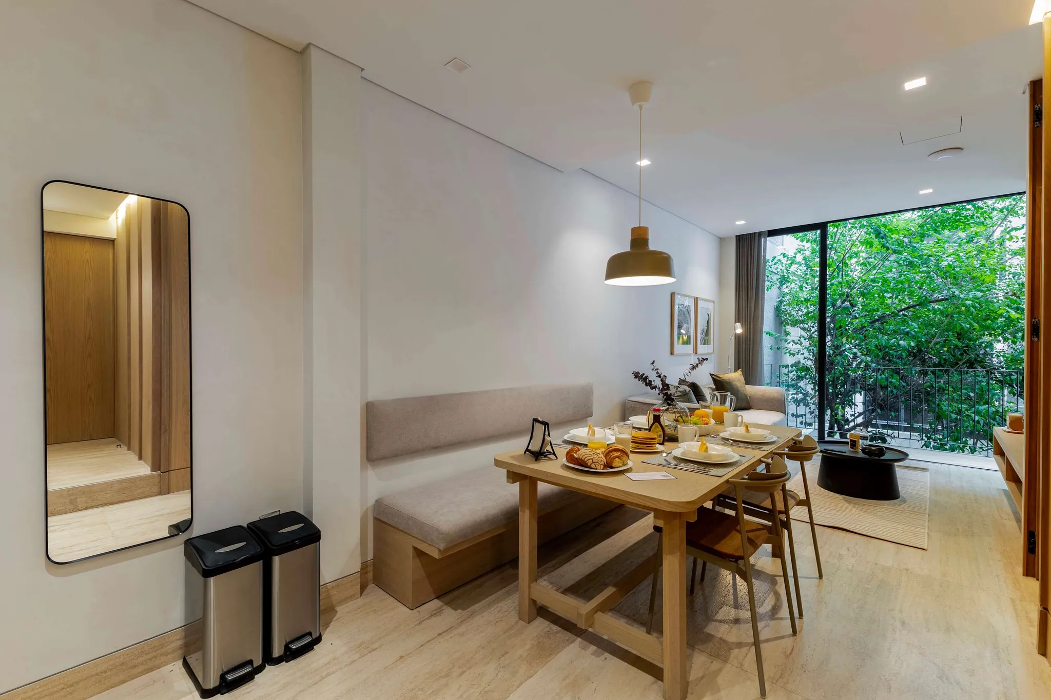 A bright dining area with a table set for breakfast and a large window overlooking lush trees.