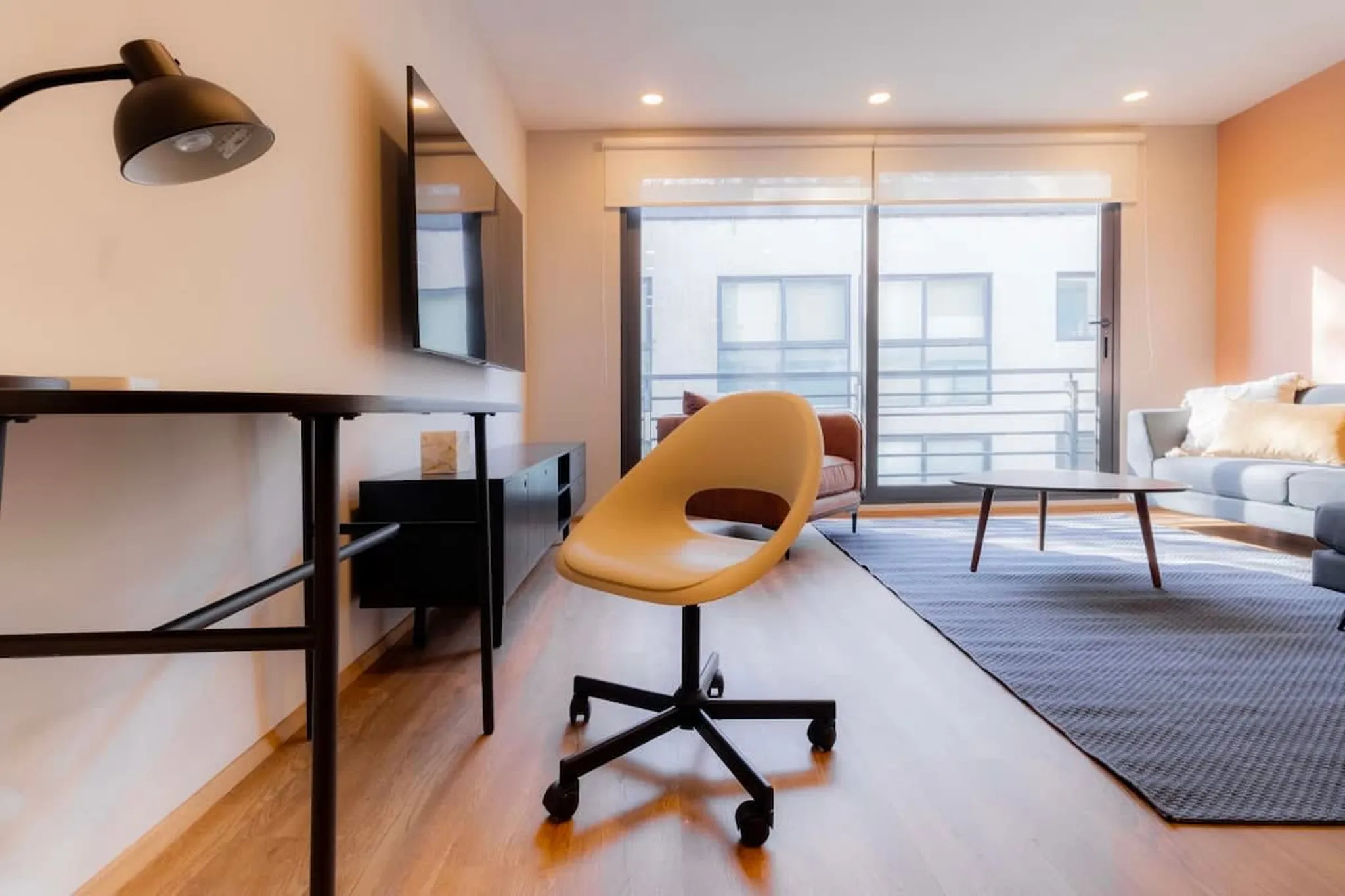 A desk with a task lamp and an orange chair in a Galileo Residences living room.