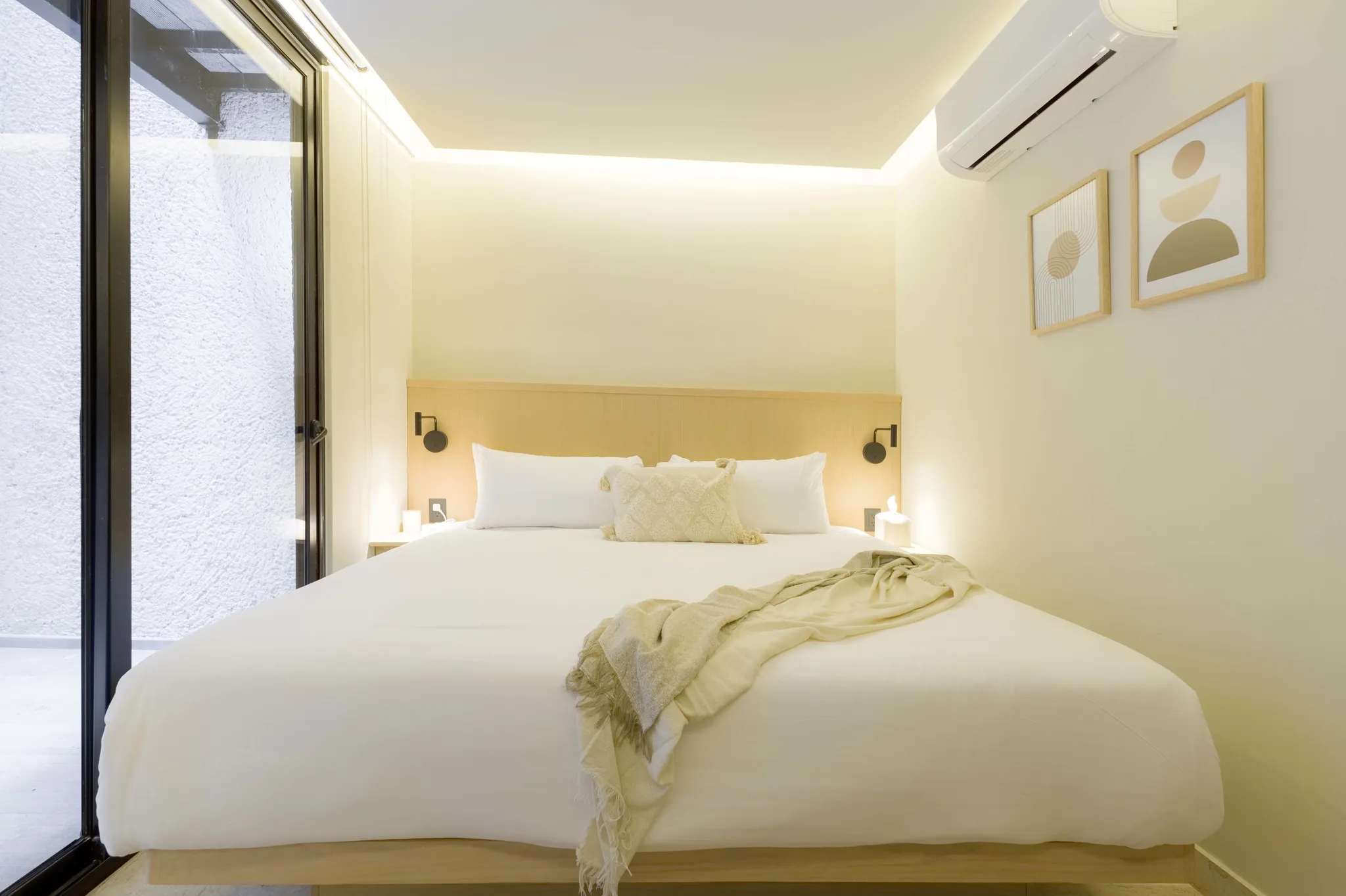 Modern bedroom with large bed, patterned throw, and abstract art.