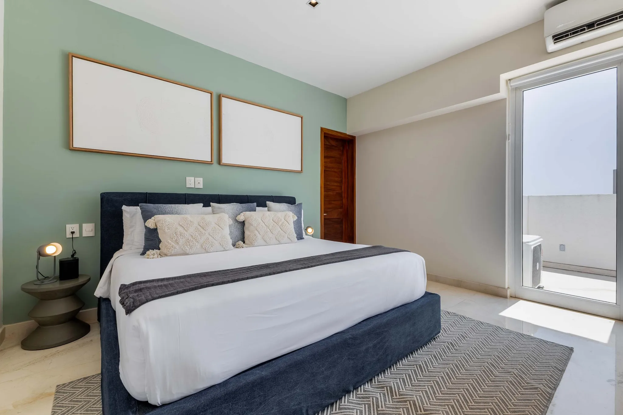 Bedroom with a large bed, green walls, and a sliding glass door.
