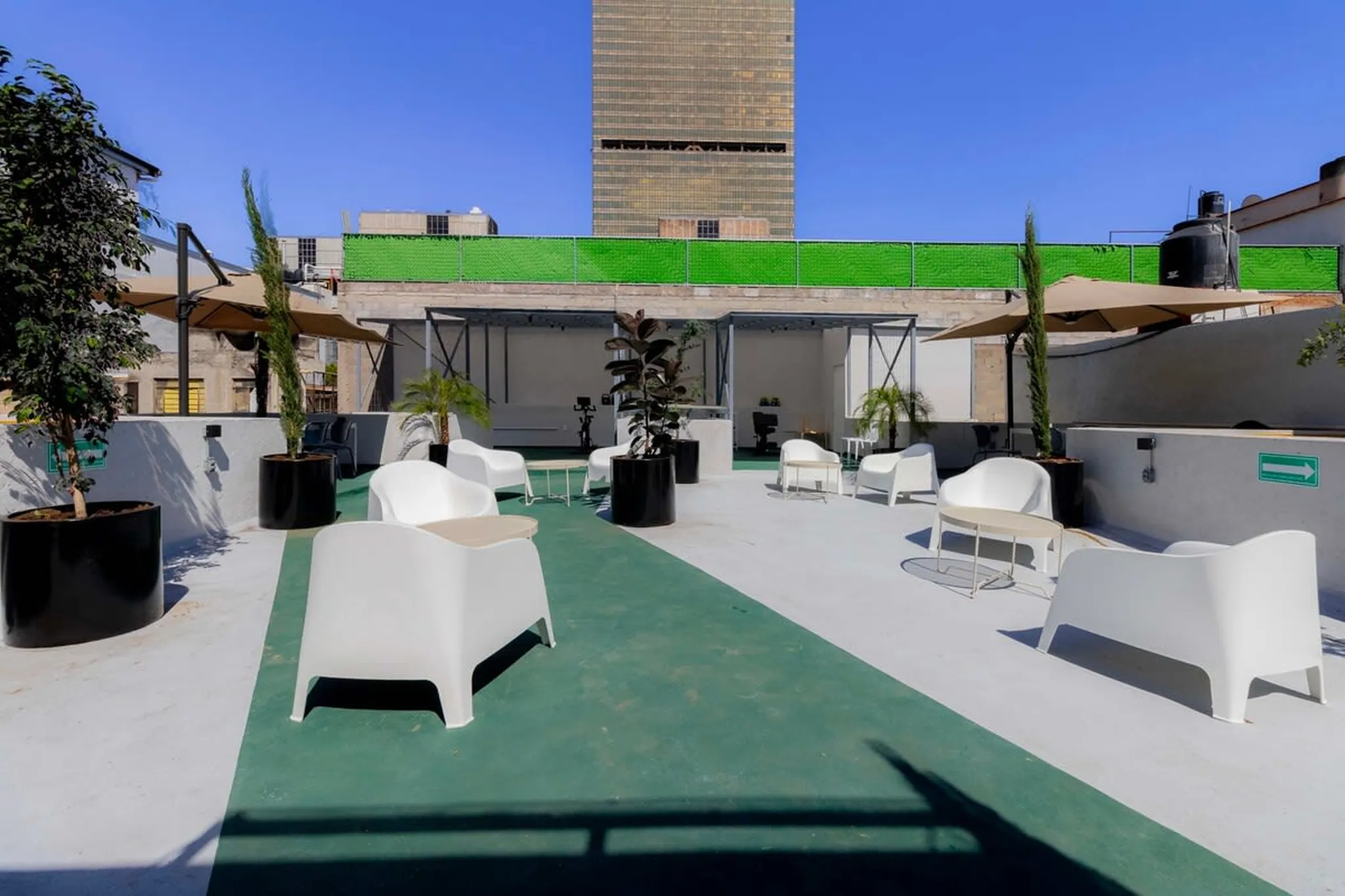 Rooftop patio with white chairs and tables under a blue sky.