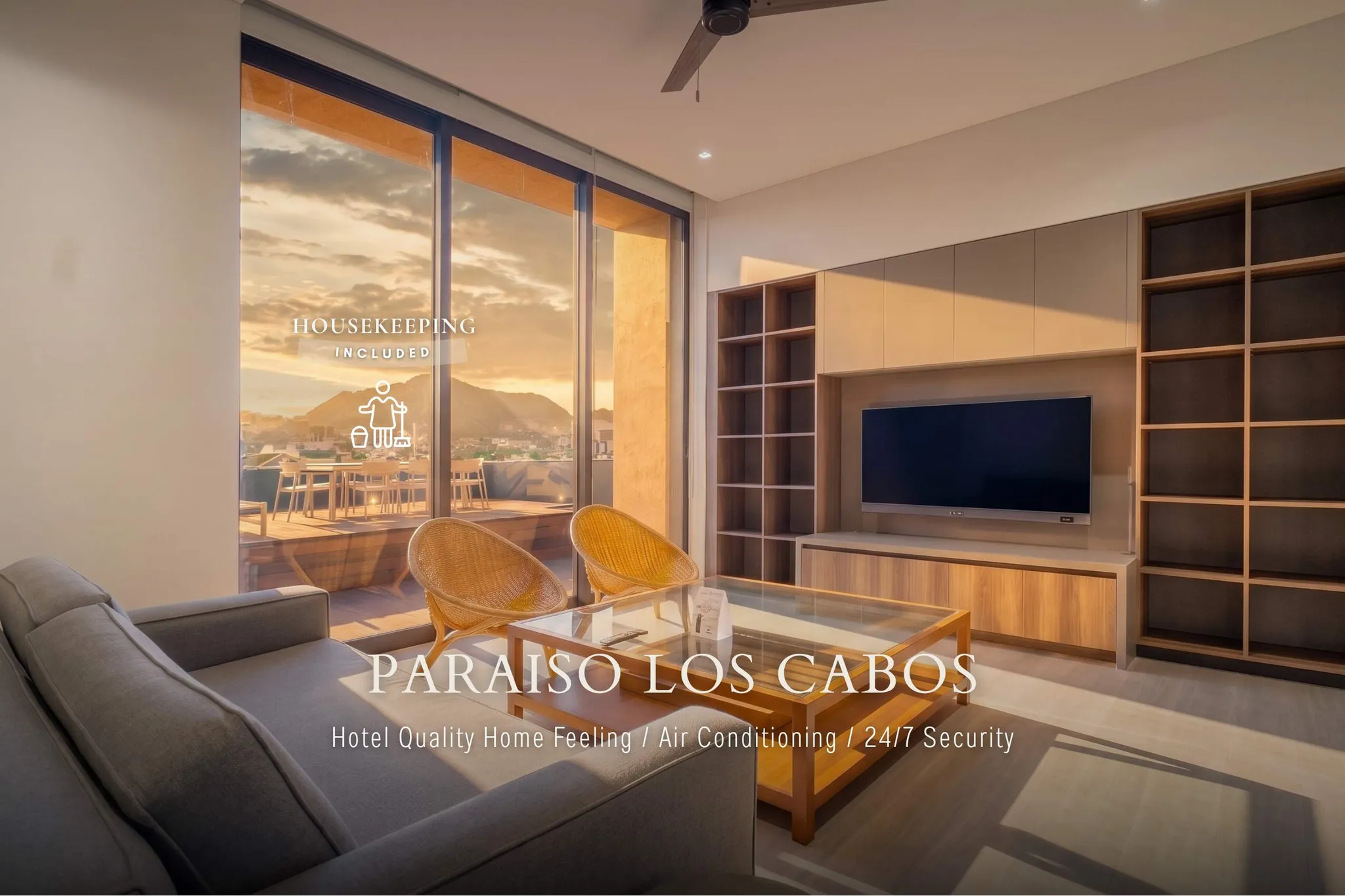 A living room with a view of a sunset over a city. "Paraiso Los Cabos" is written on the couch.