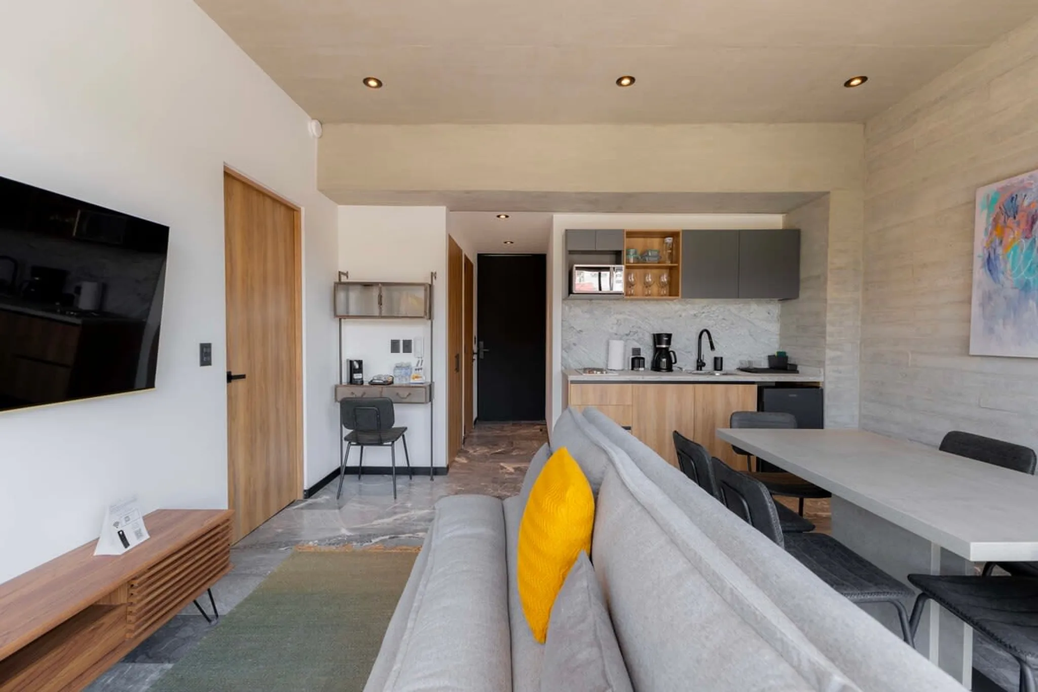 Modern living room with a TV, kitchen, and dining area.