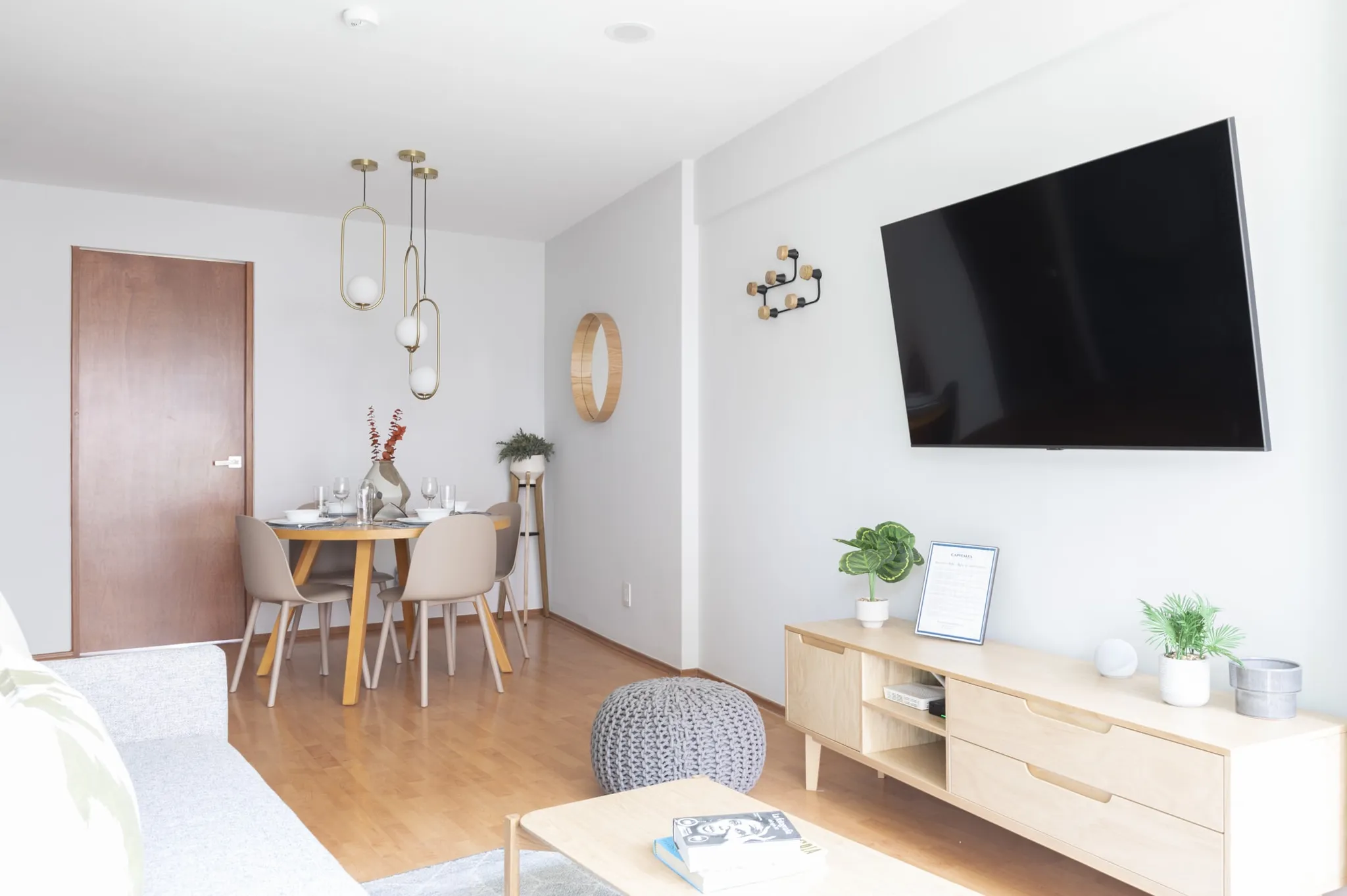 A modern living room with a dining table, TV, and wooden furniture.