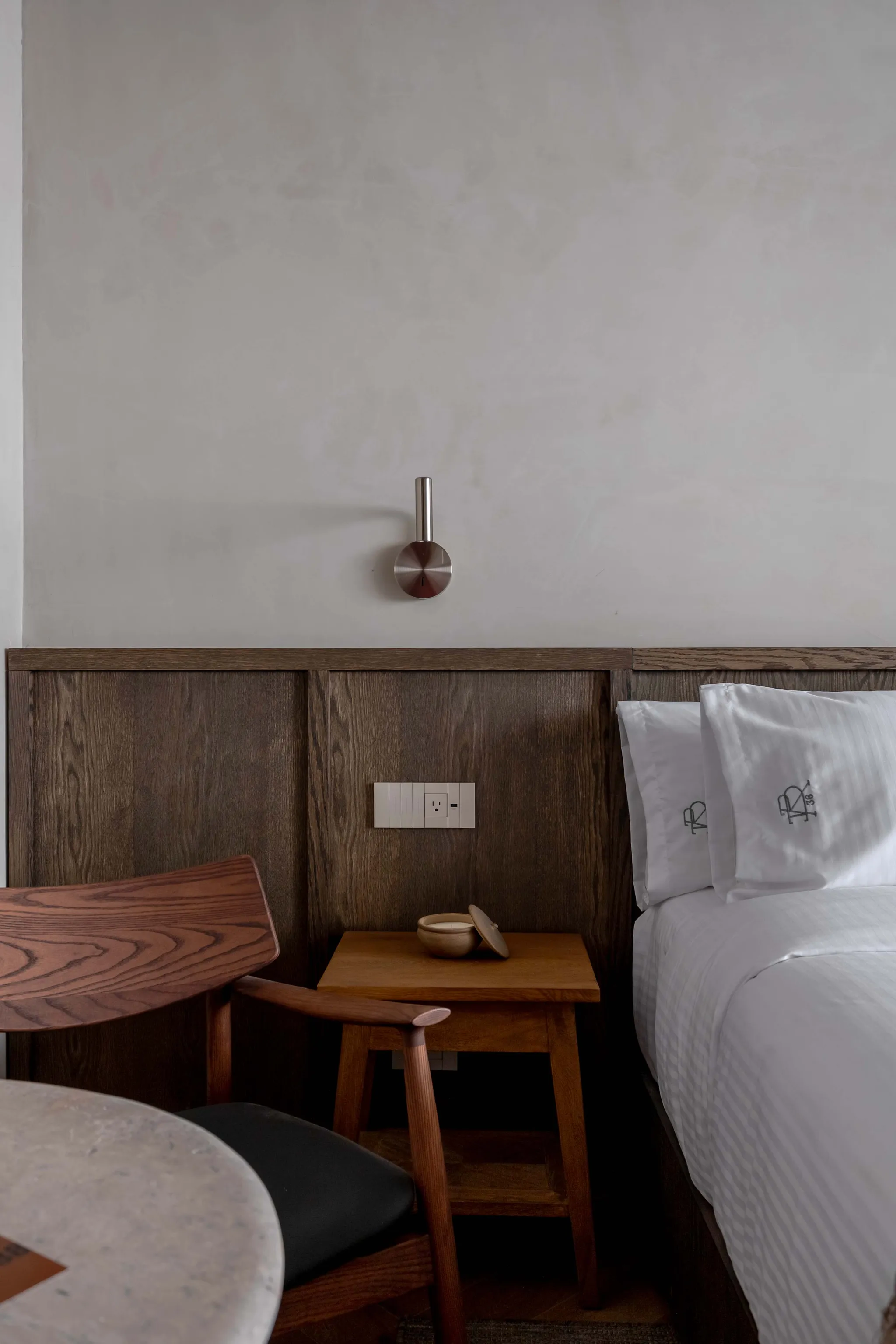 A cozy bedroom features a bed with white striped linens and a wooden chair.