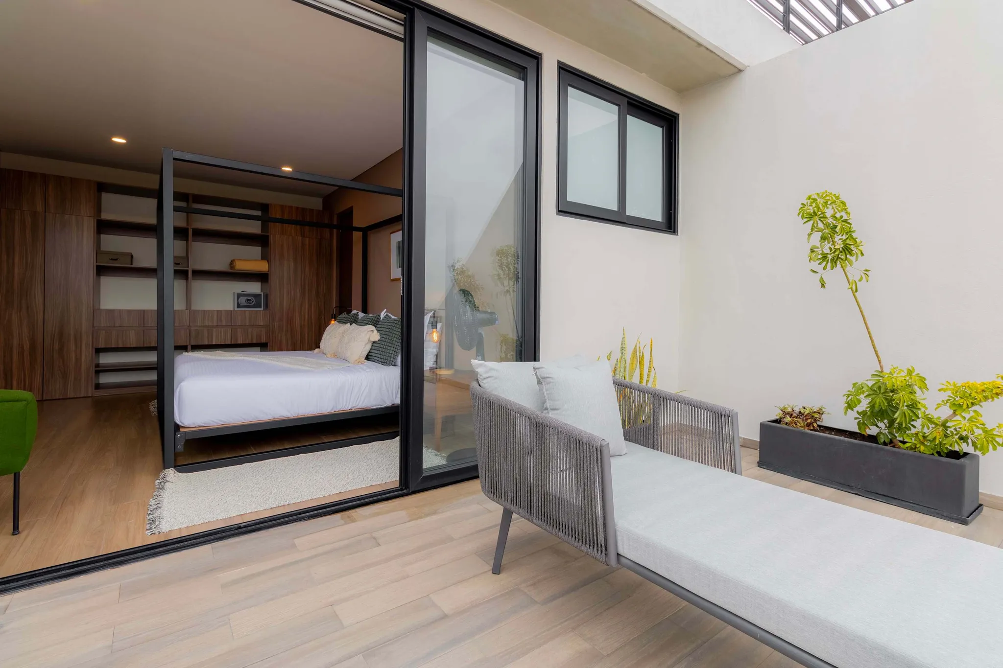 Modern bedroom with a canopy bed and outdoor lounge area.