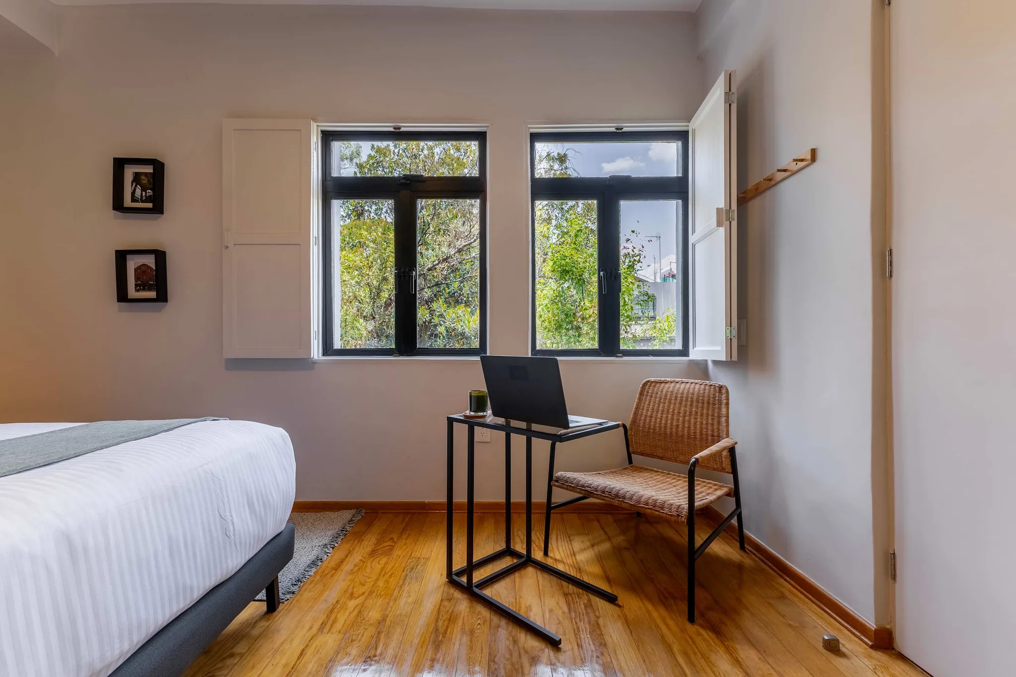 Bedroom with bed, desk, chair, and window with greenery outside.