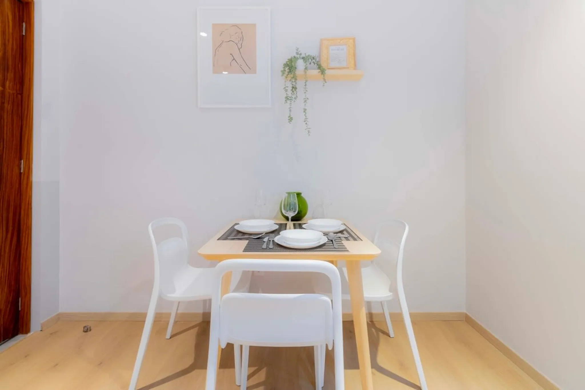 A small dining set with white chairs and a light wood table.