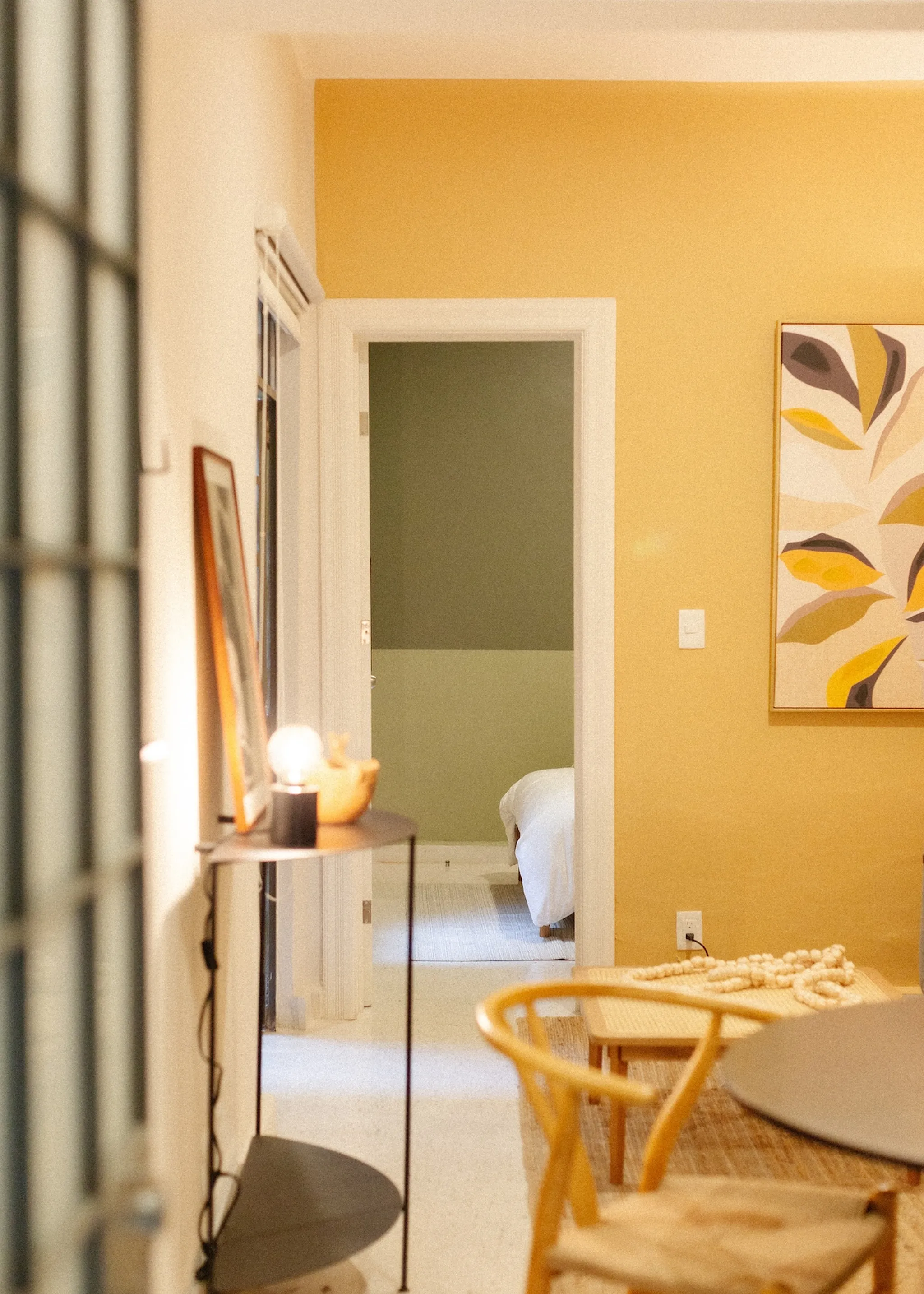 Interior shot of a bedroom with yellow walls and a wooden chair.