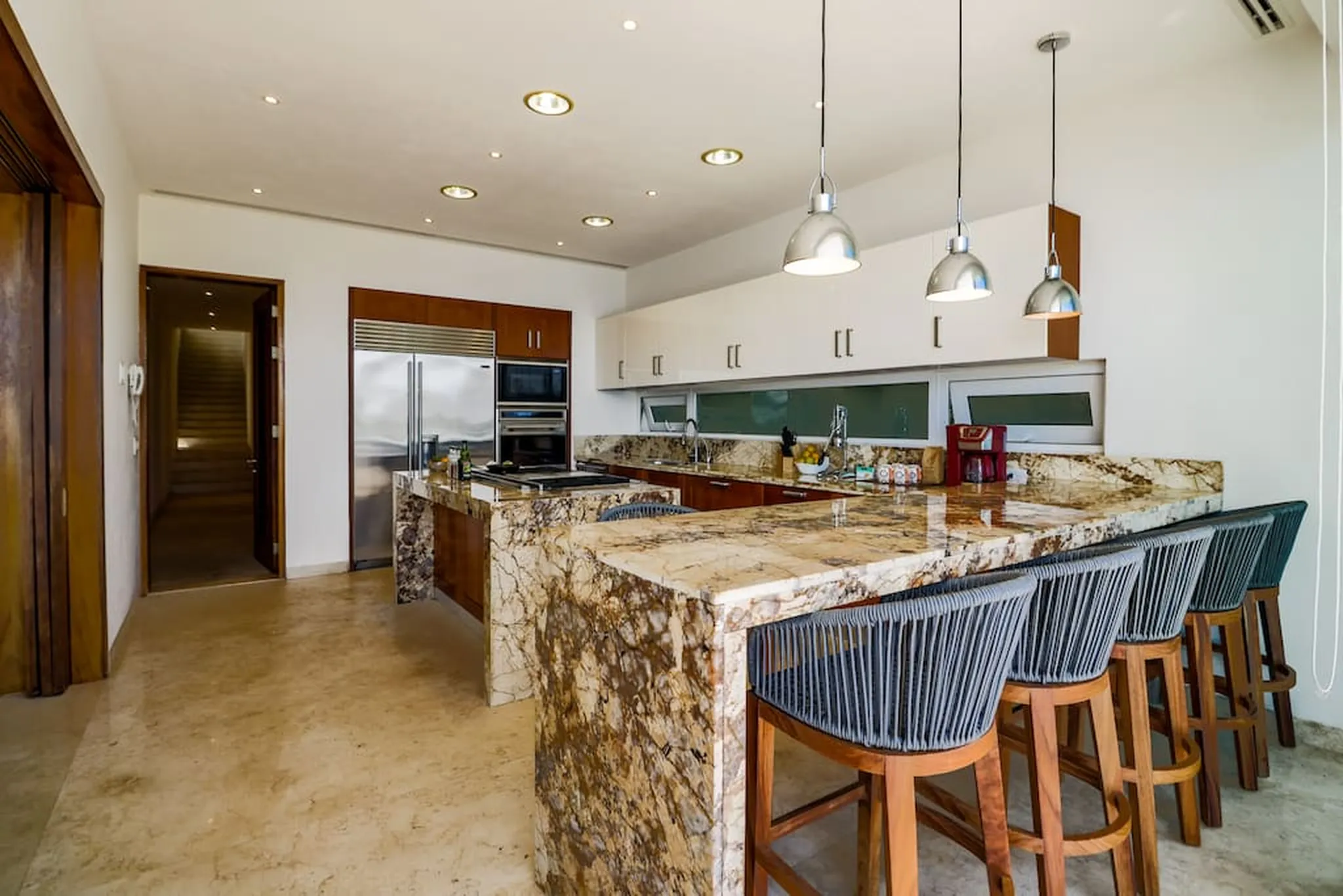 A modern kitchen with a granite island and bar stools.
