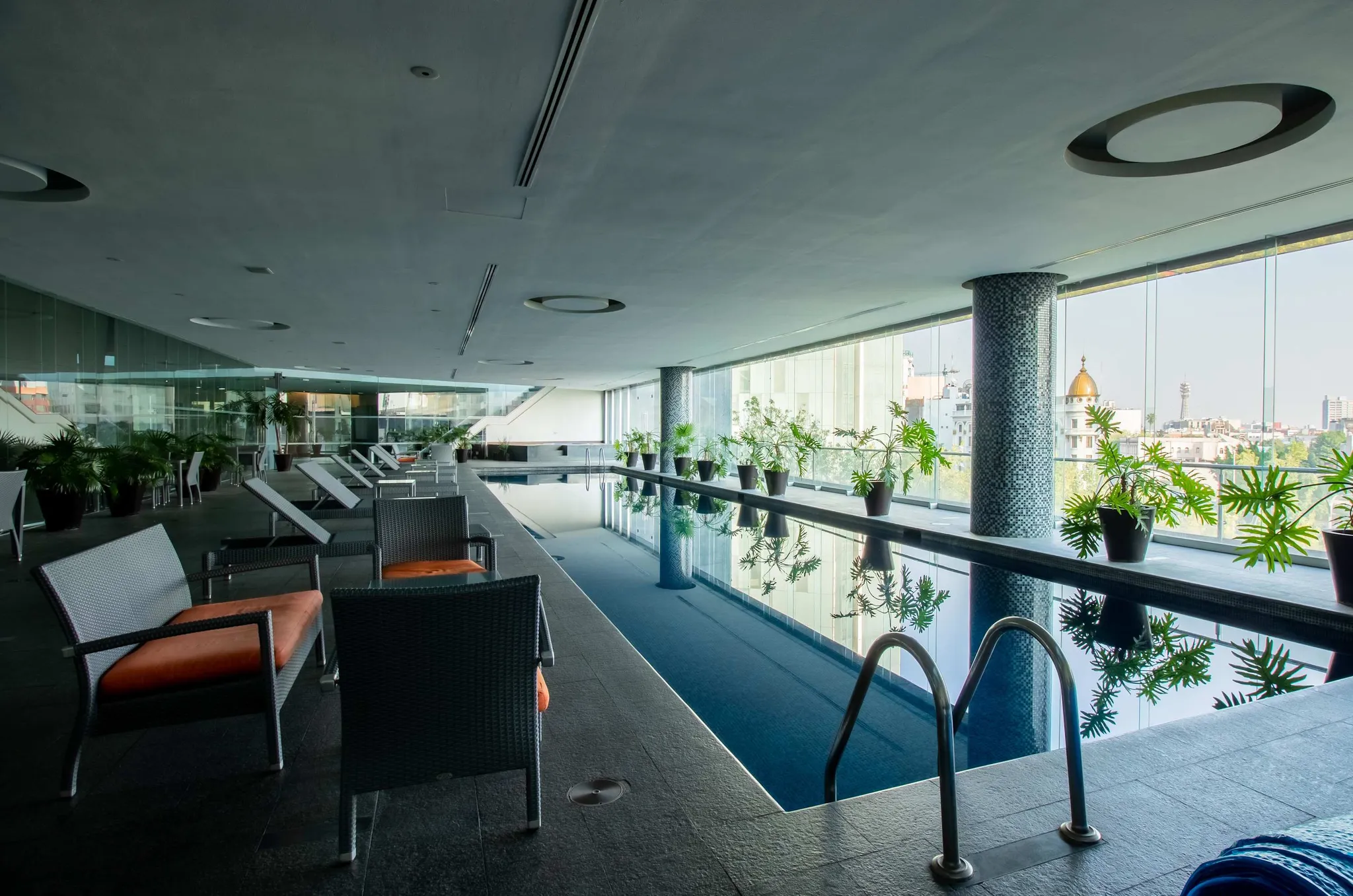 An indoor swimming pool with lounge chairs and potted plants.
