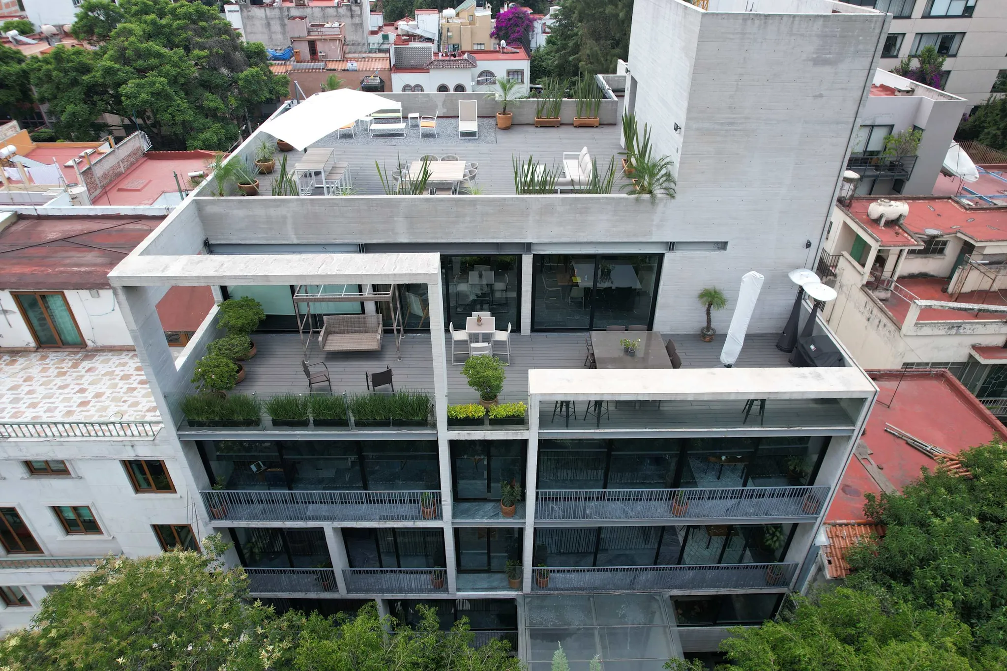 An aerial view of a modern building with balconies and rooftop seating.
