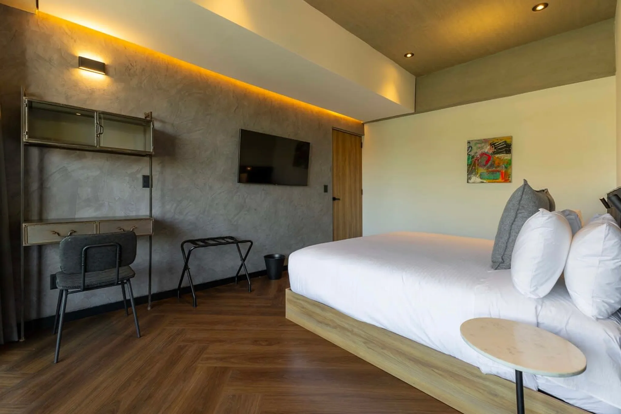 A modern bedroom with a desk, chair, bed, and artwork.