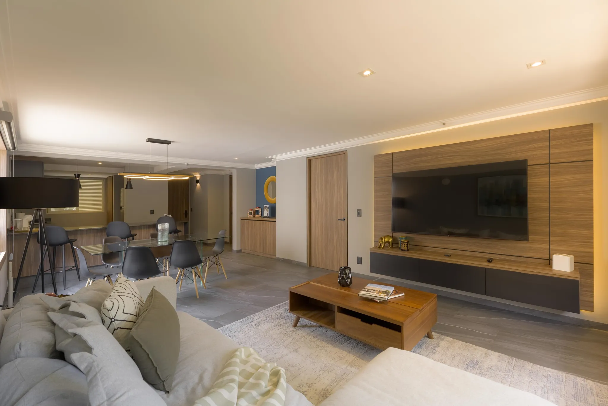 A modern living room with a large TV, a wooden entertainment center, and a sofa.