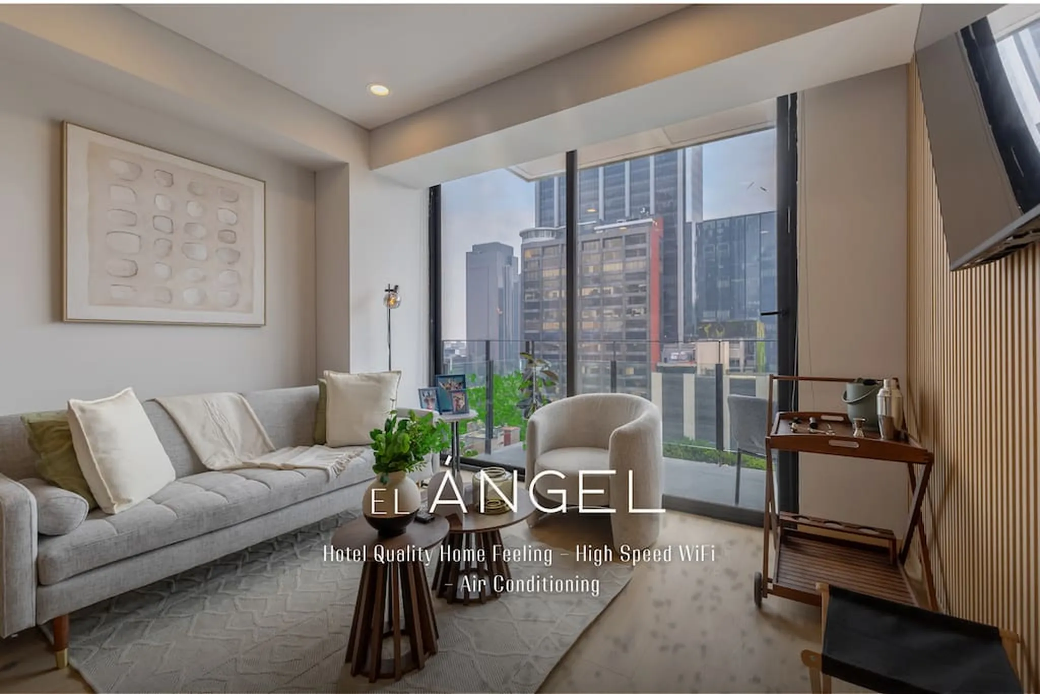 Living room with a gray sofa, armchair, coffee table, and city view through a large window.
