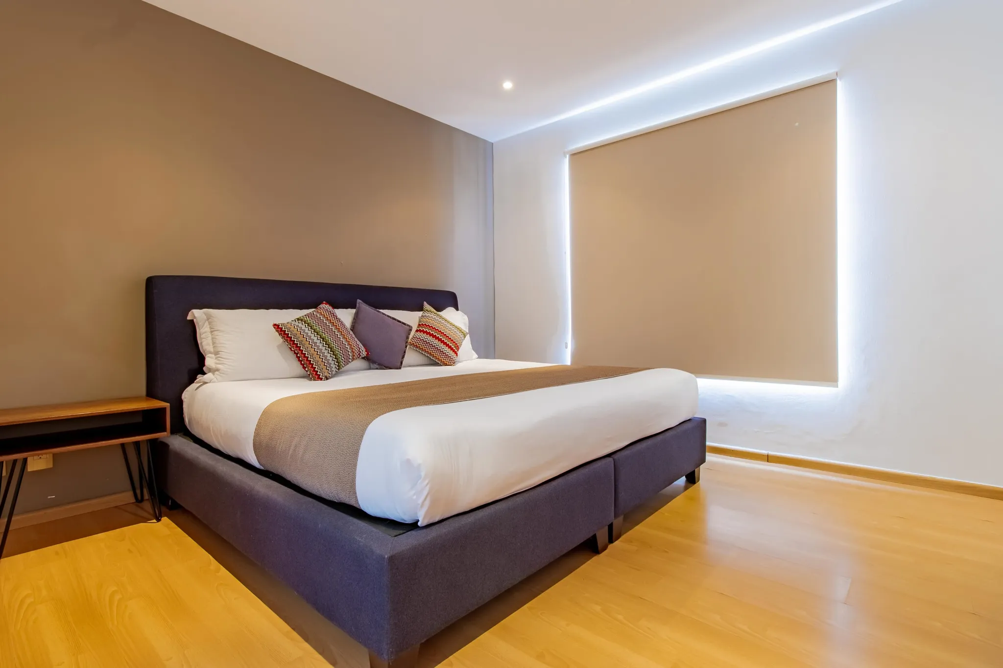 A modern bedroom with a king-size bed, minimalist decor, and ambient lighting.