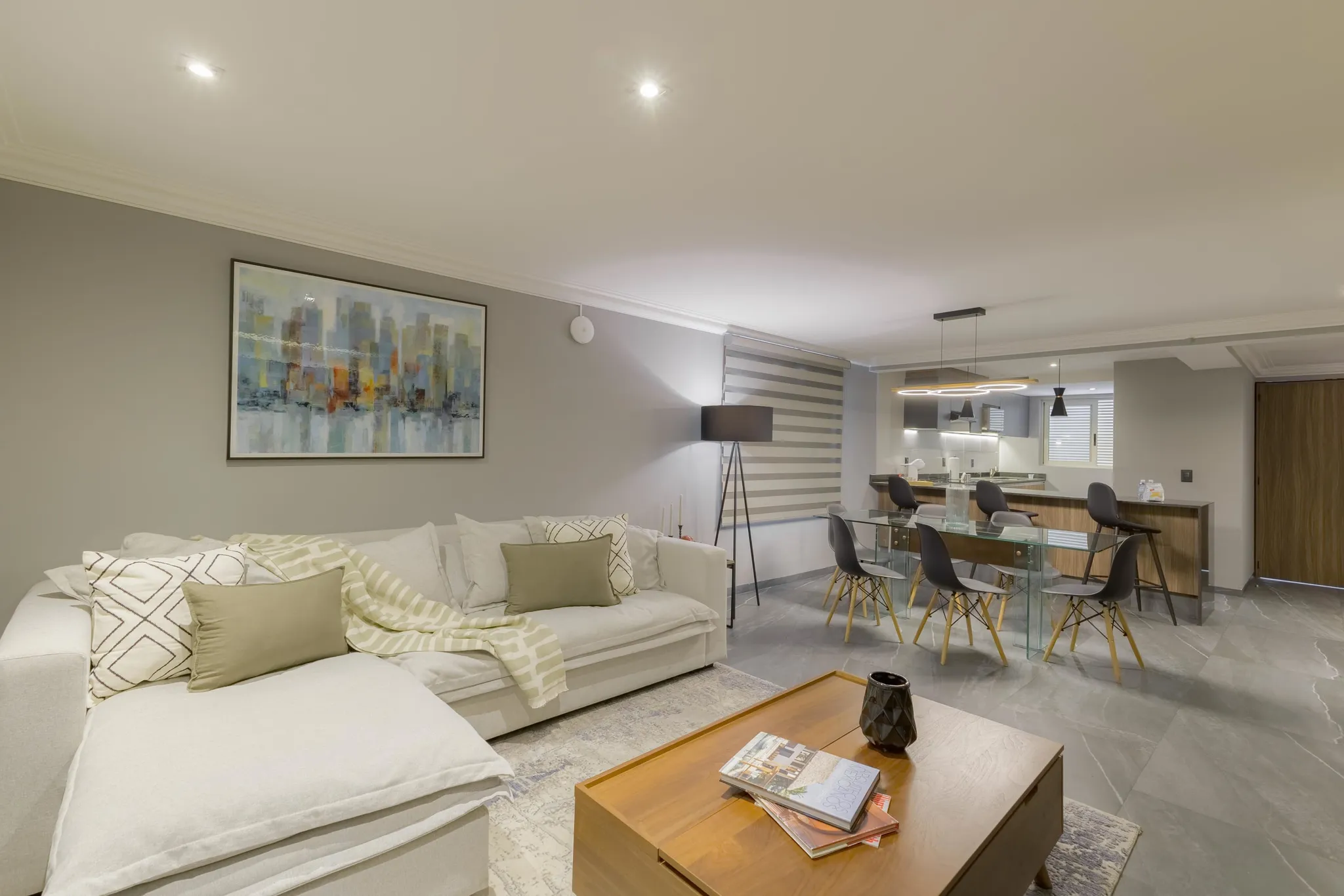 Modern living room with sectional sofa, dining table and chairs, and a contemporary painting.