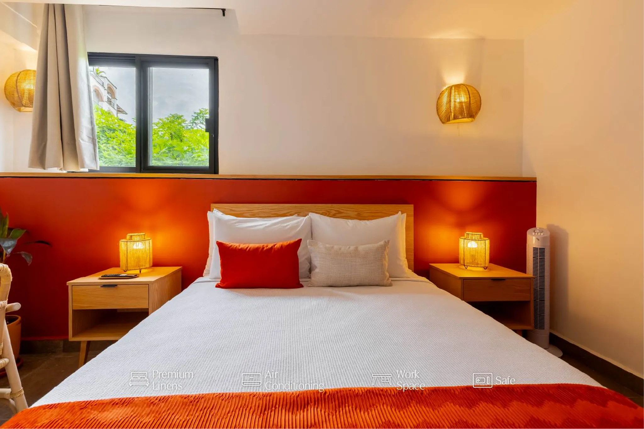 A hotel bedroom with a bright red accent wall and a large bed.