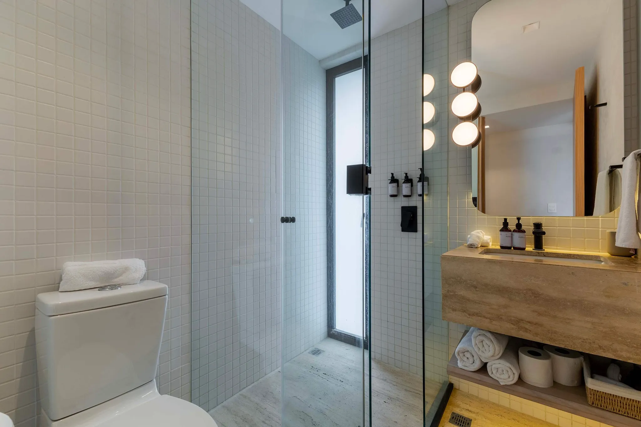 A modern bathroom with a toilet, shower, and vanity.