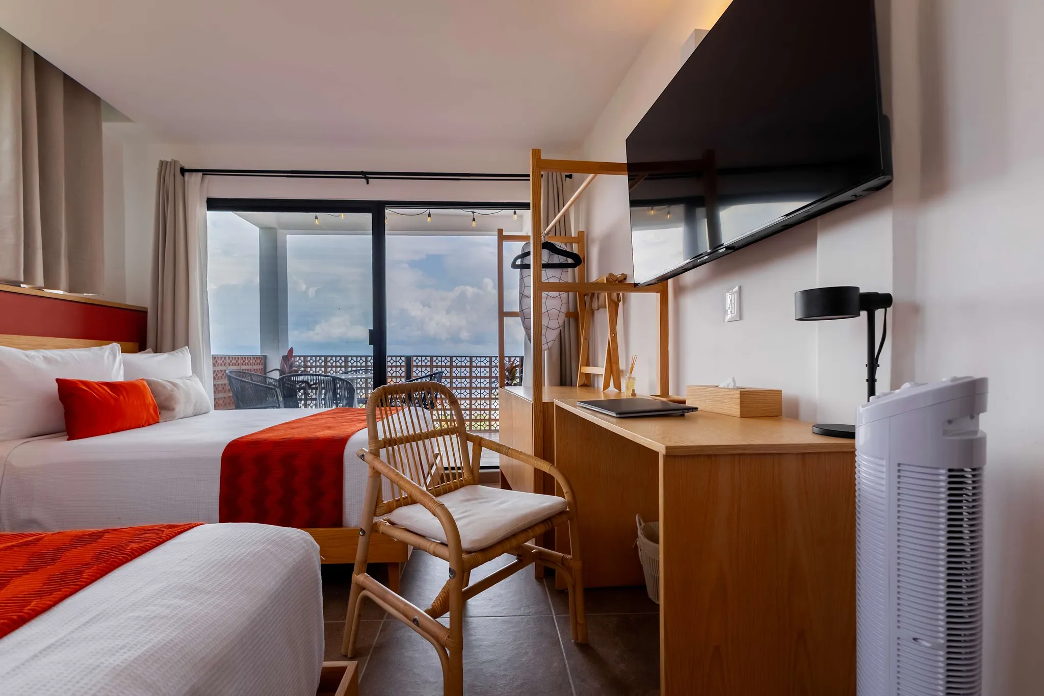 A modern hotel room with two beds, a desk, and a TV.