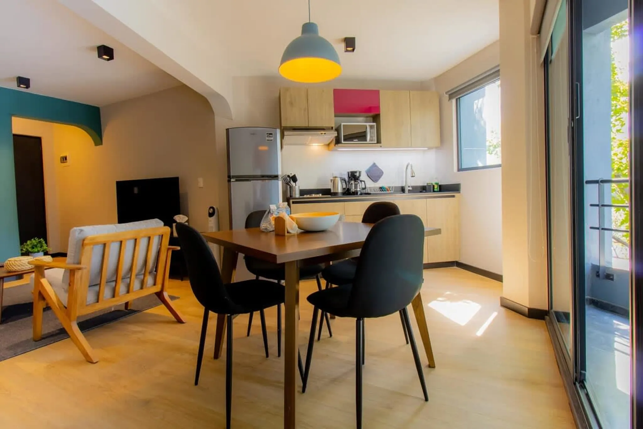 A modern living and dining area with a kitchen, refrigerator, and dining table with chairs.