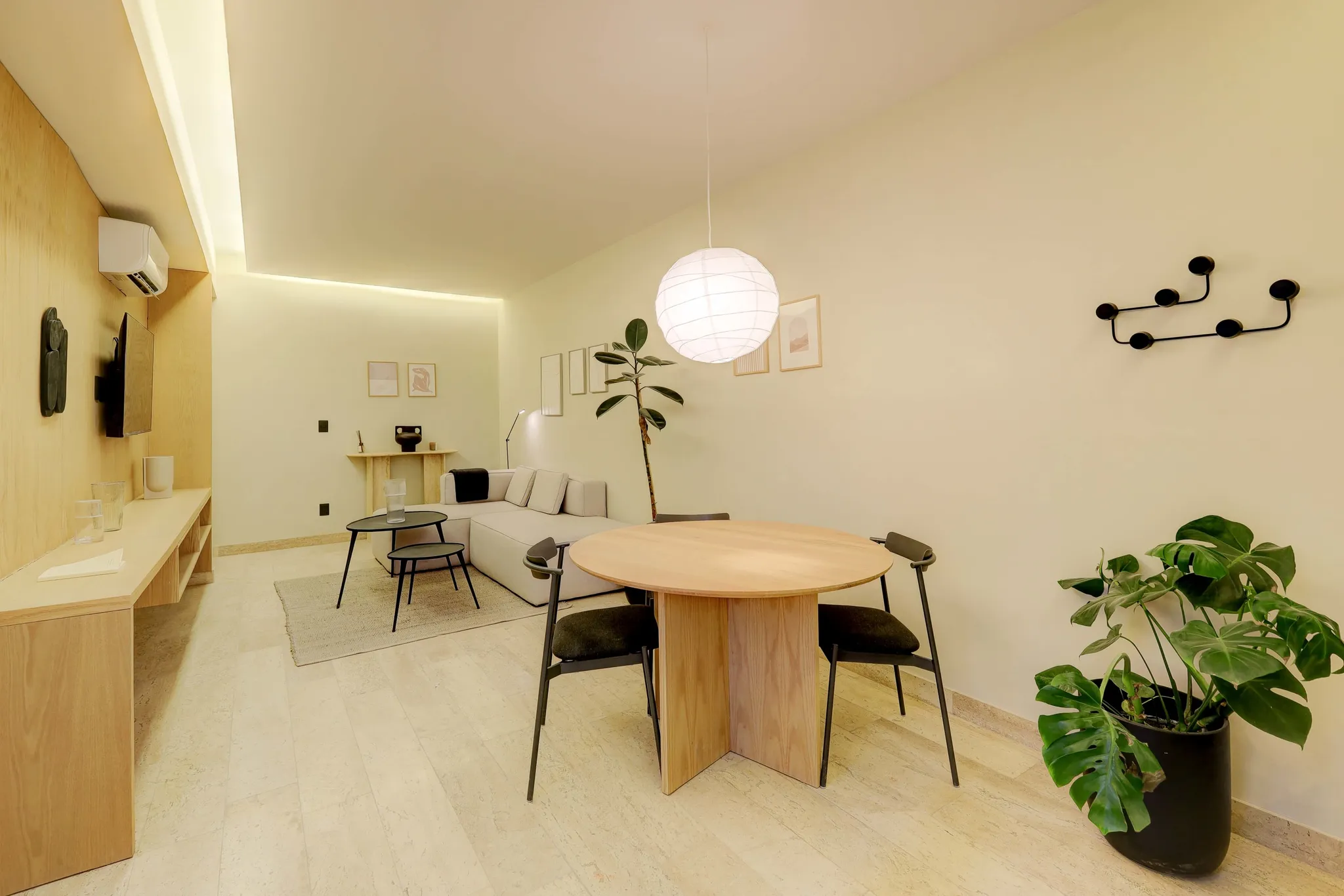 A modern living room with a sofa, dining table, and large plant.