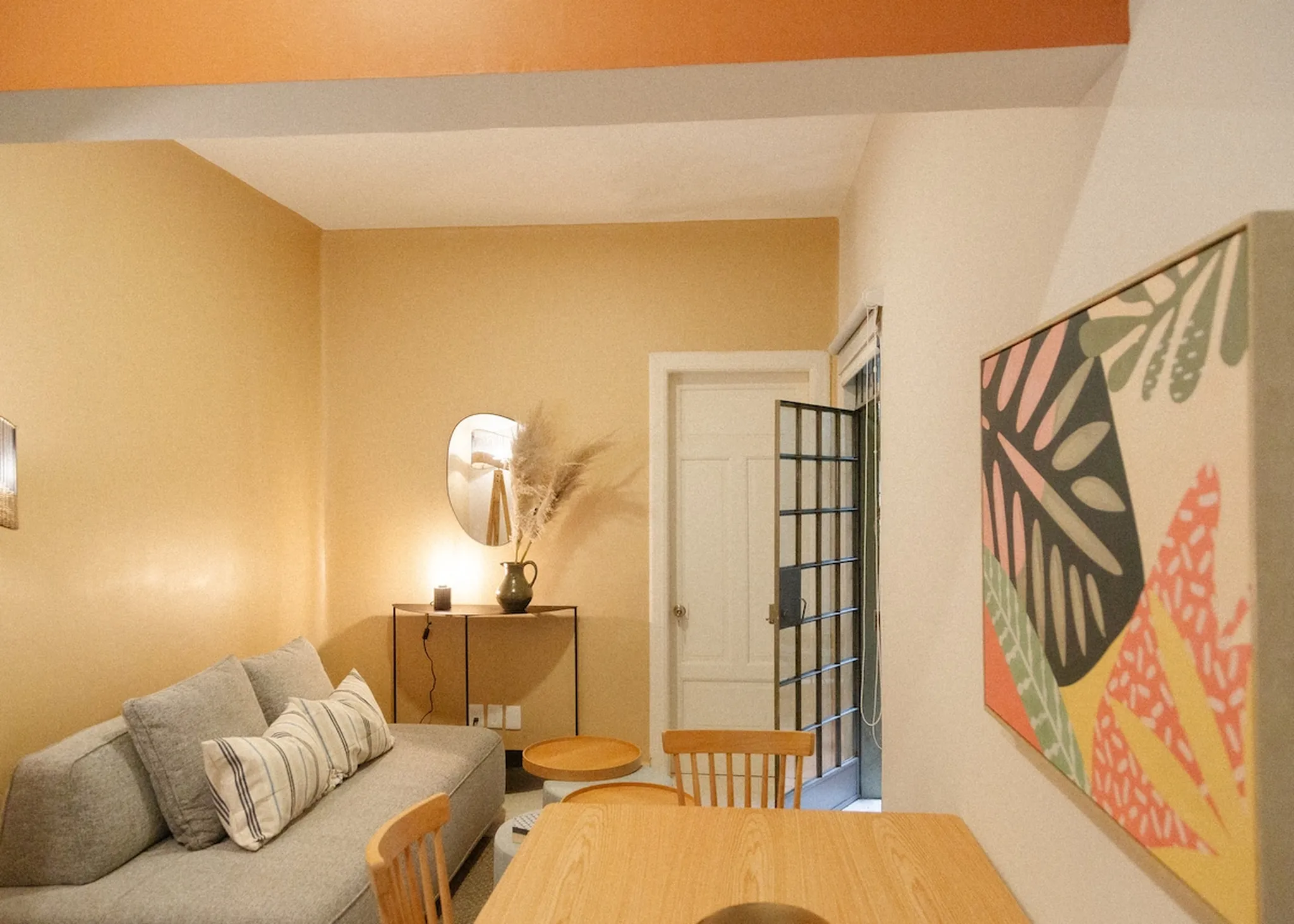 A living room with a gray couch, a table, chairs, and wall art.