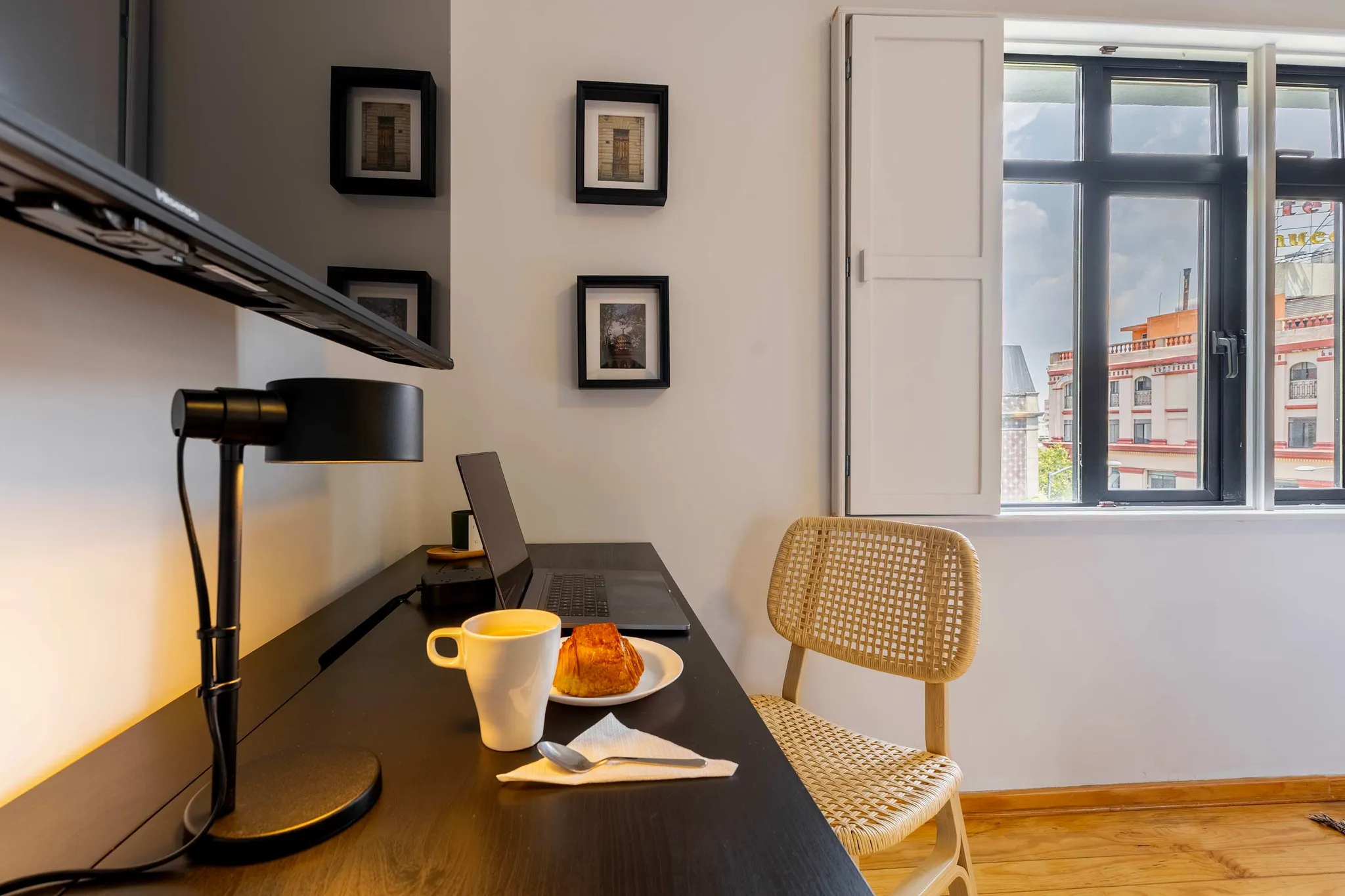 A workspace setup with a laptop, coffee, and a pastry.
