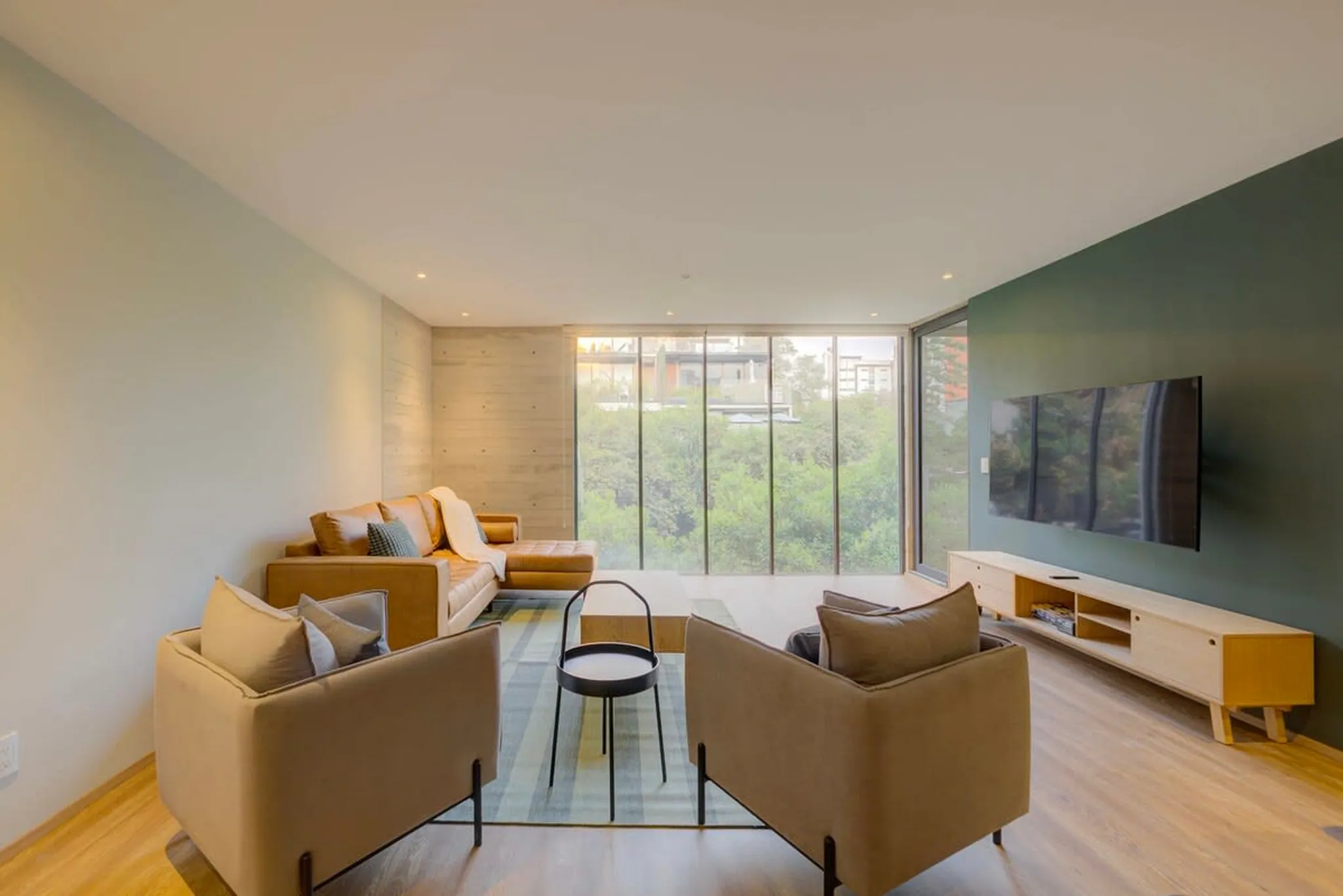 A modern living room with a leather sectional sofa, accent chairs, and a wall-mounted TV.