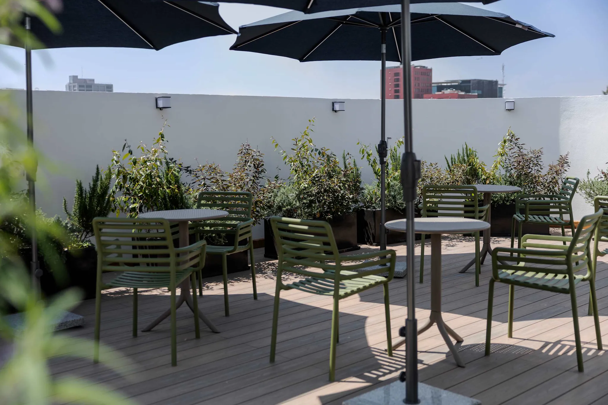 An outdoor patio with green chairs, tables, and umbrellas.