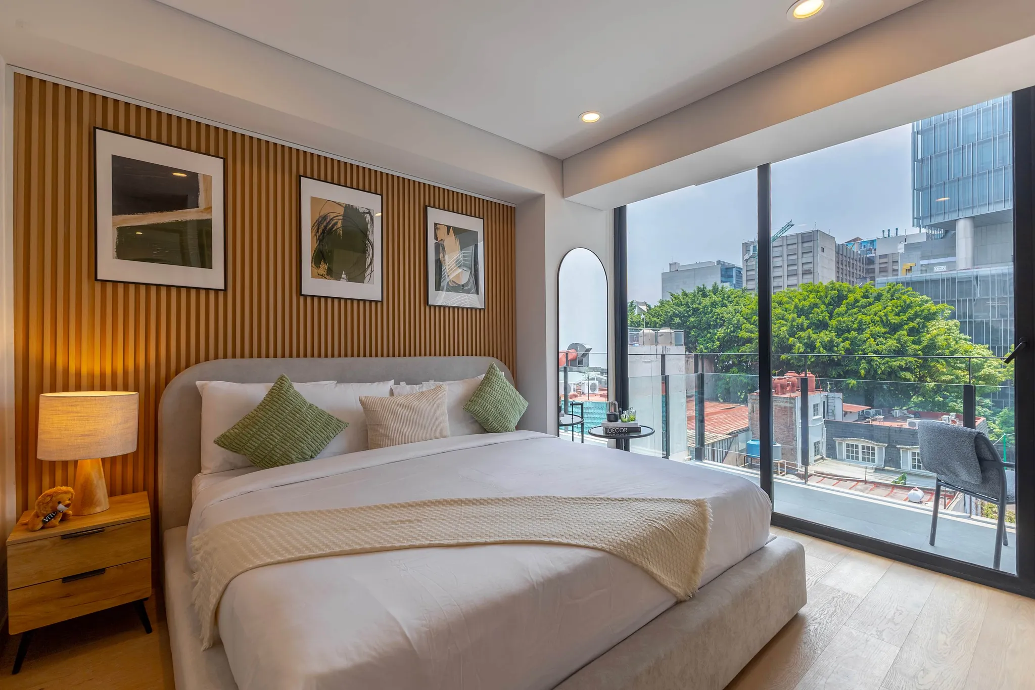 Modern bedroom with a large bed, wooden wall paneling, and a floor-to-ceiling window with city views