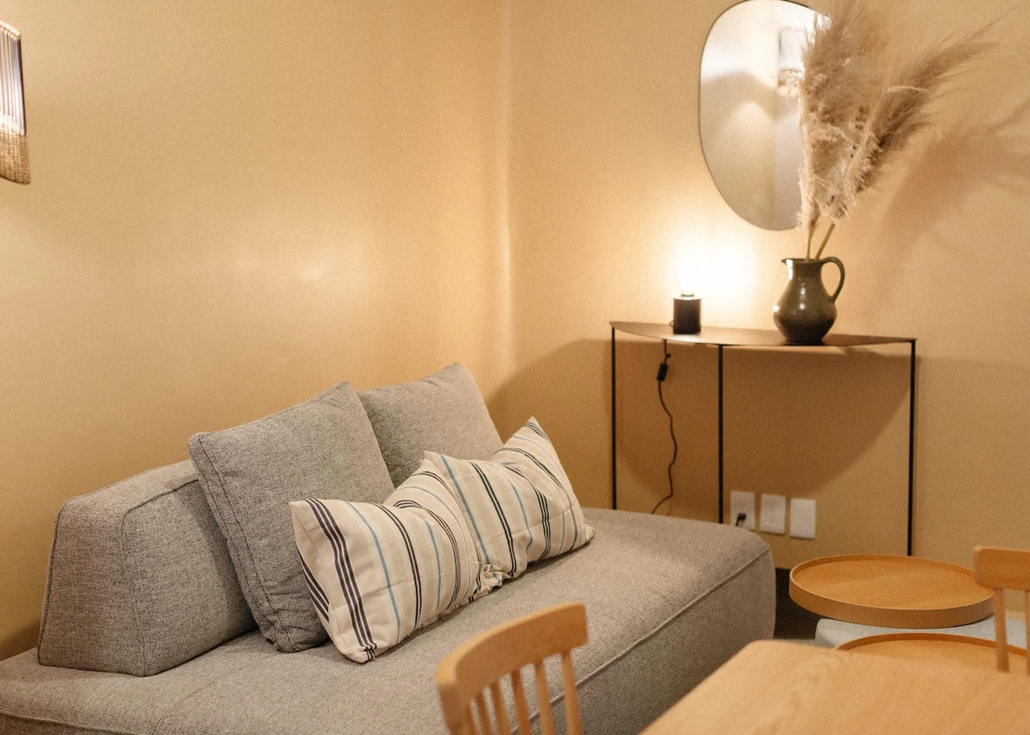 A couch with pillows and a console table with a lamp and vase.