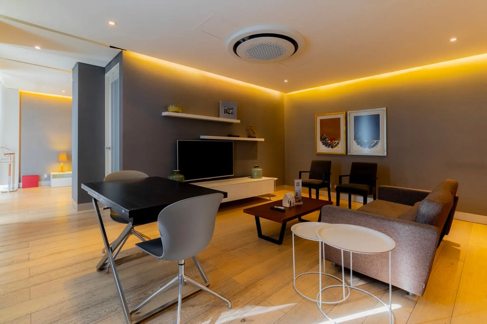 Living room with dining table, chairs, tv, coffee table, armchair, and artwork on wall.