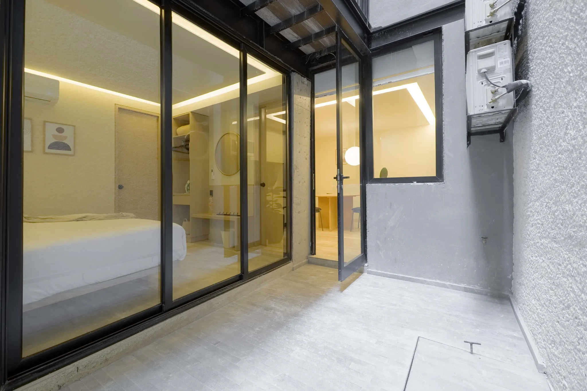 An interior view of a bedroom with a bed and a closet seen through glass doors.