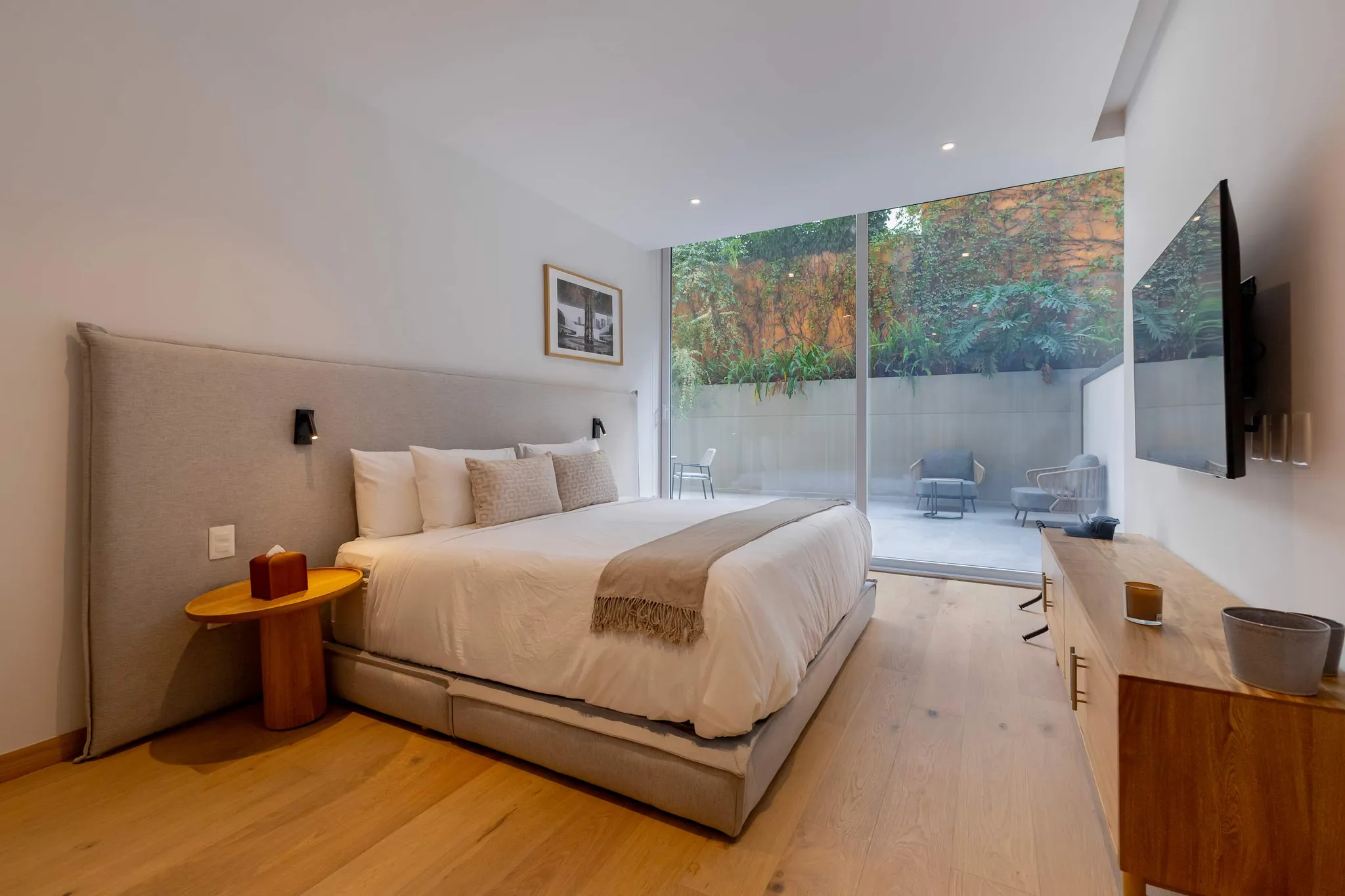 Modern bedroom with a king-size bed and large windows opening to a patio.