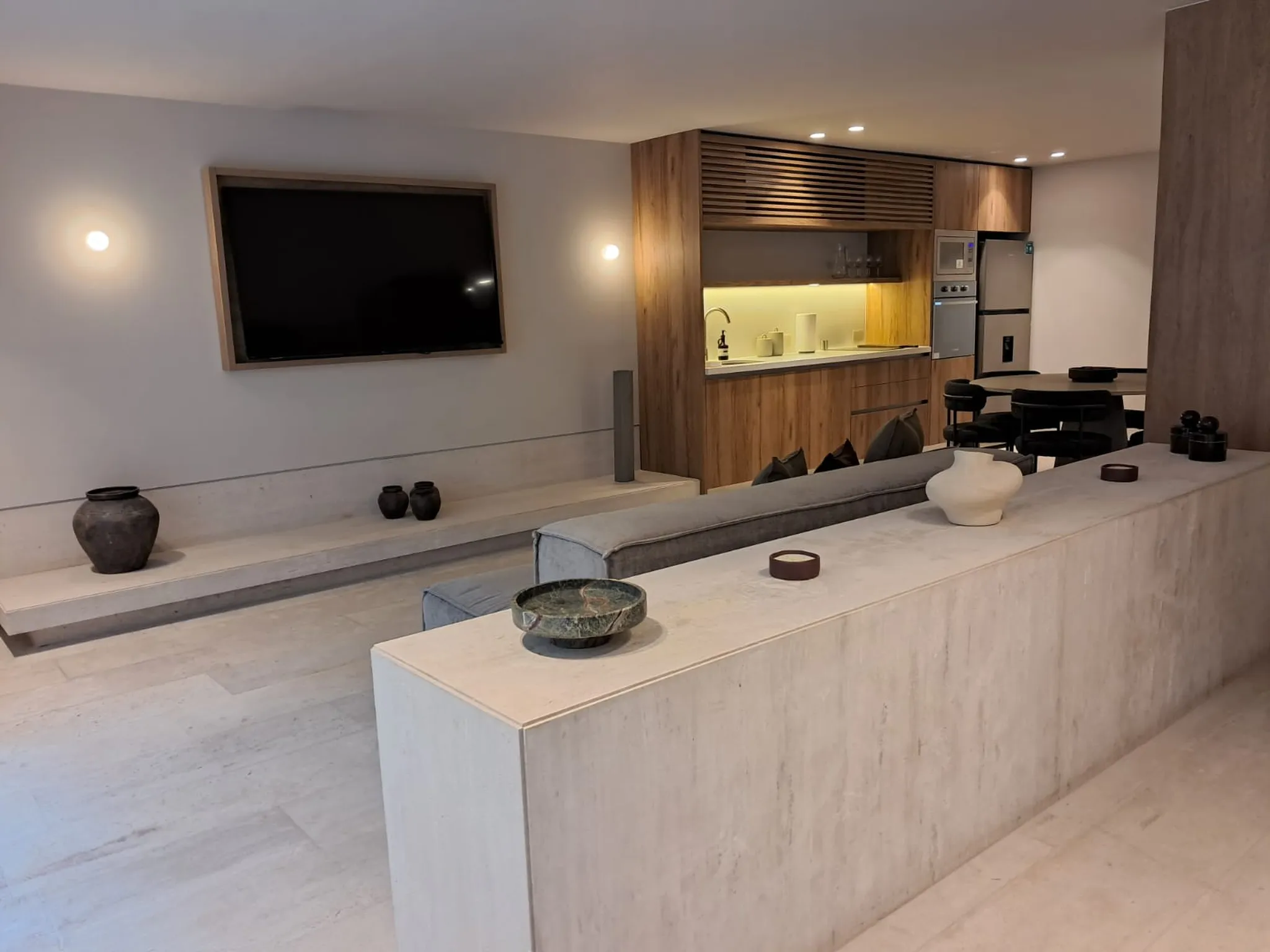 A modern living room with a TV, kitchen, and dining area.
