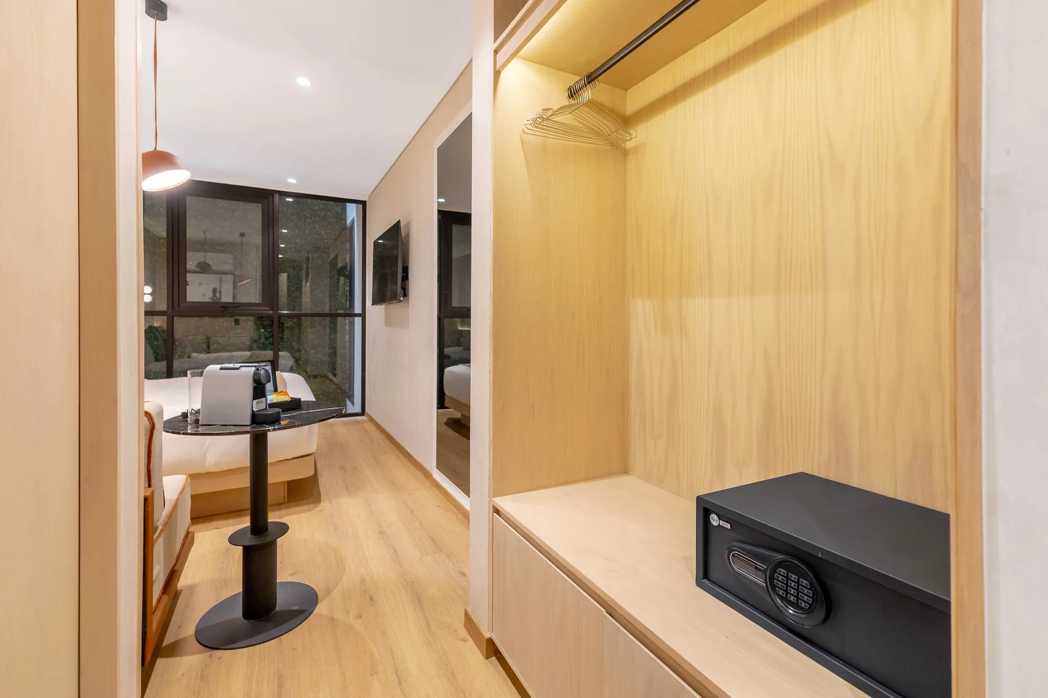 A safe is visible inside a wooden closet in a hotel room.