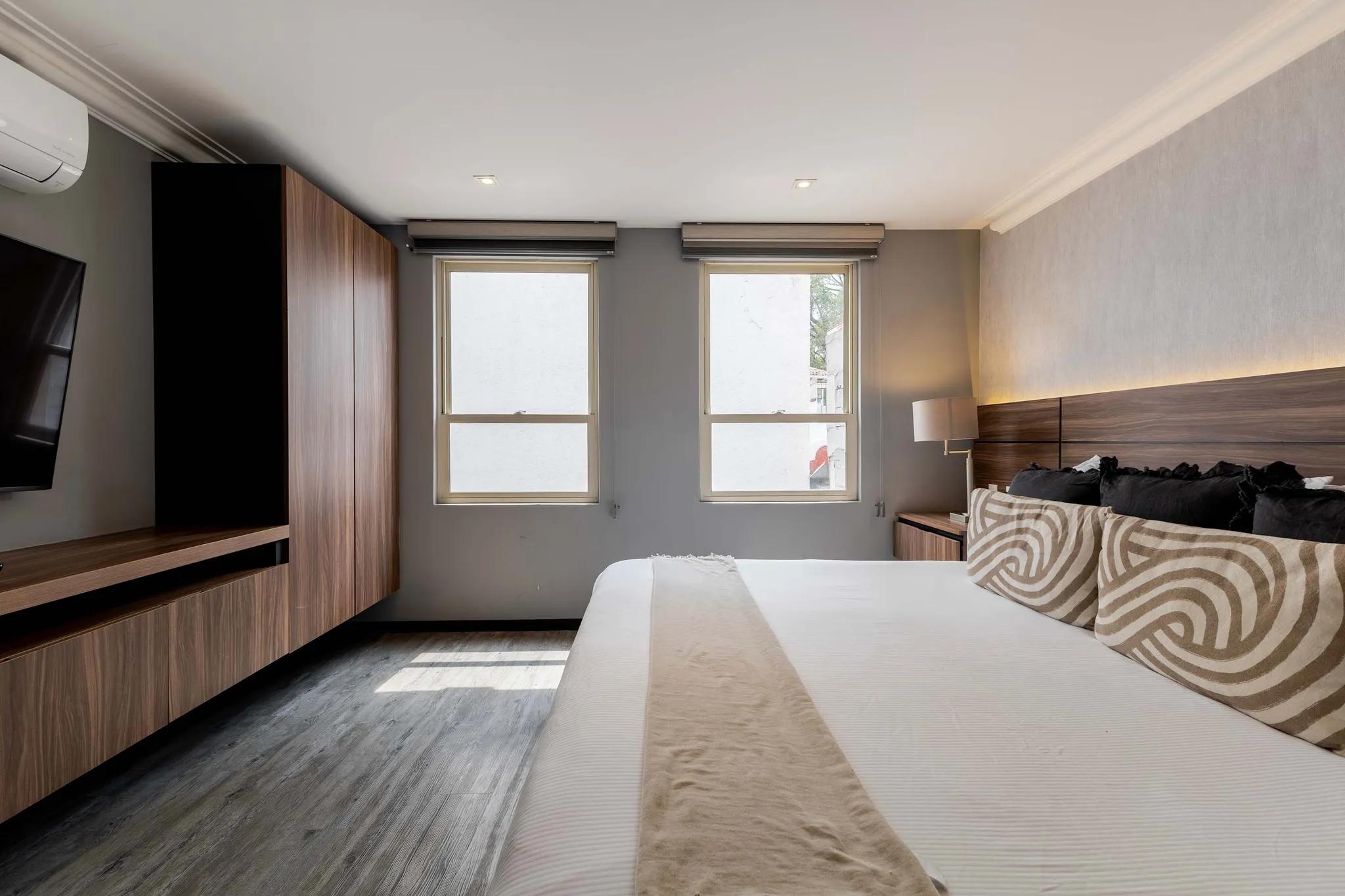Bedroom with a large bed, wooden closet, and two windows.