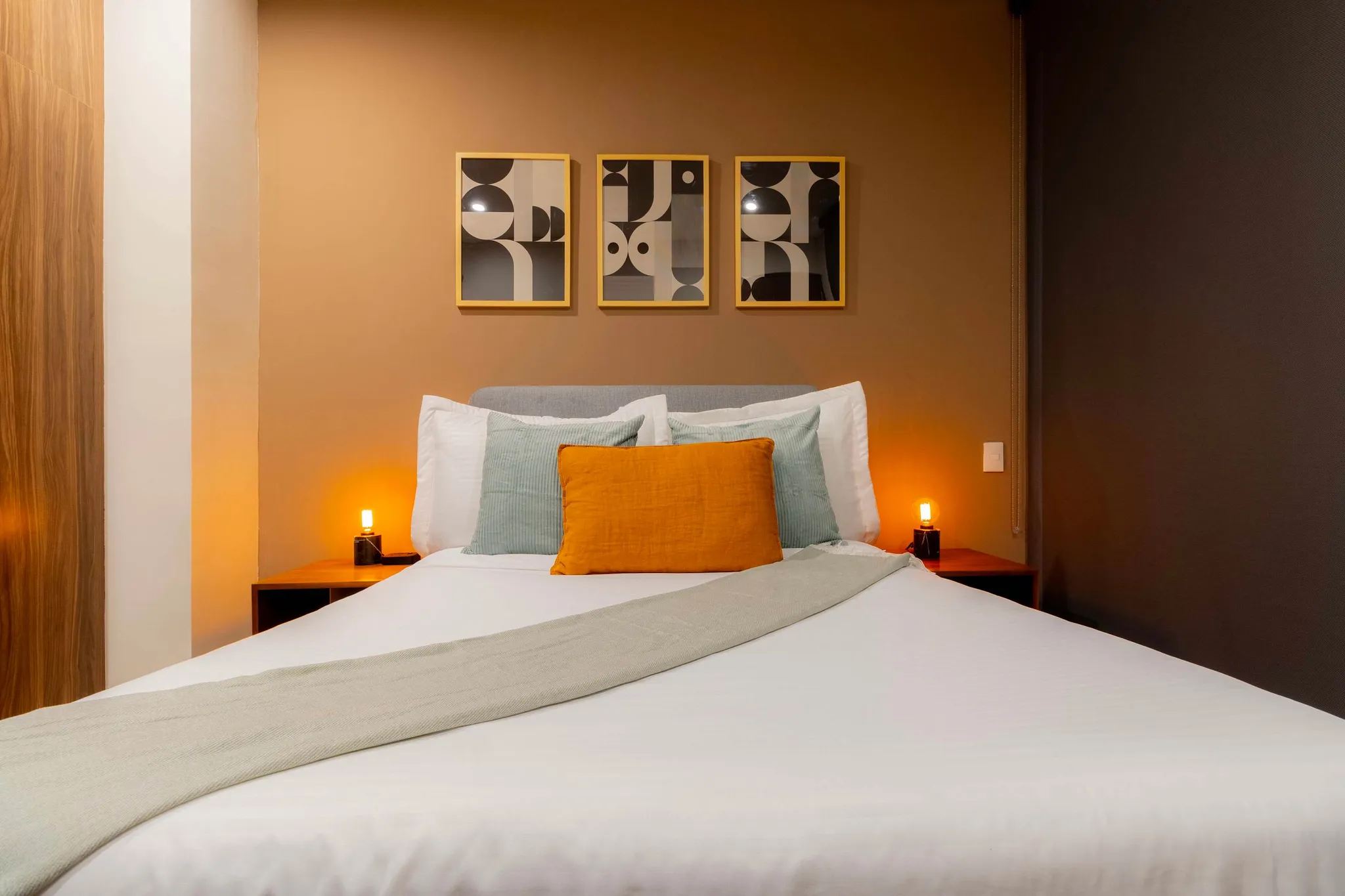 A well-made bed with white linens, decorative pillows, and a textured throw.