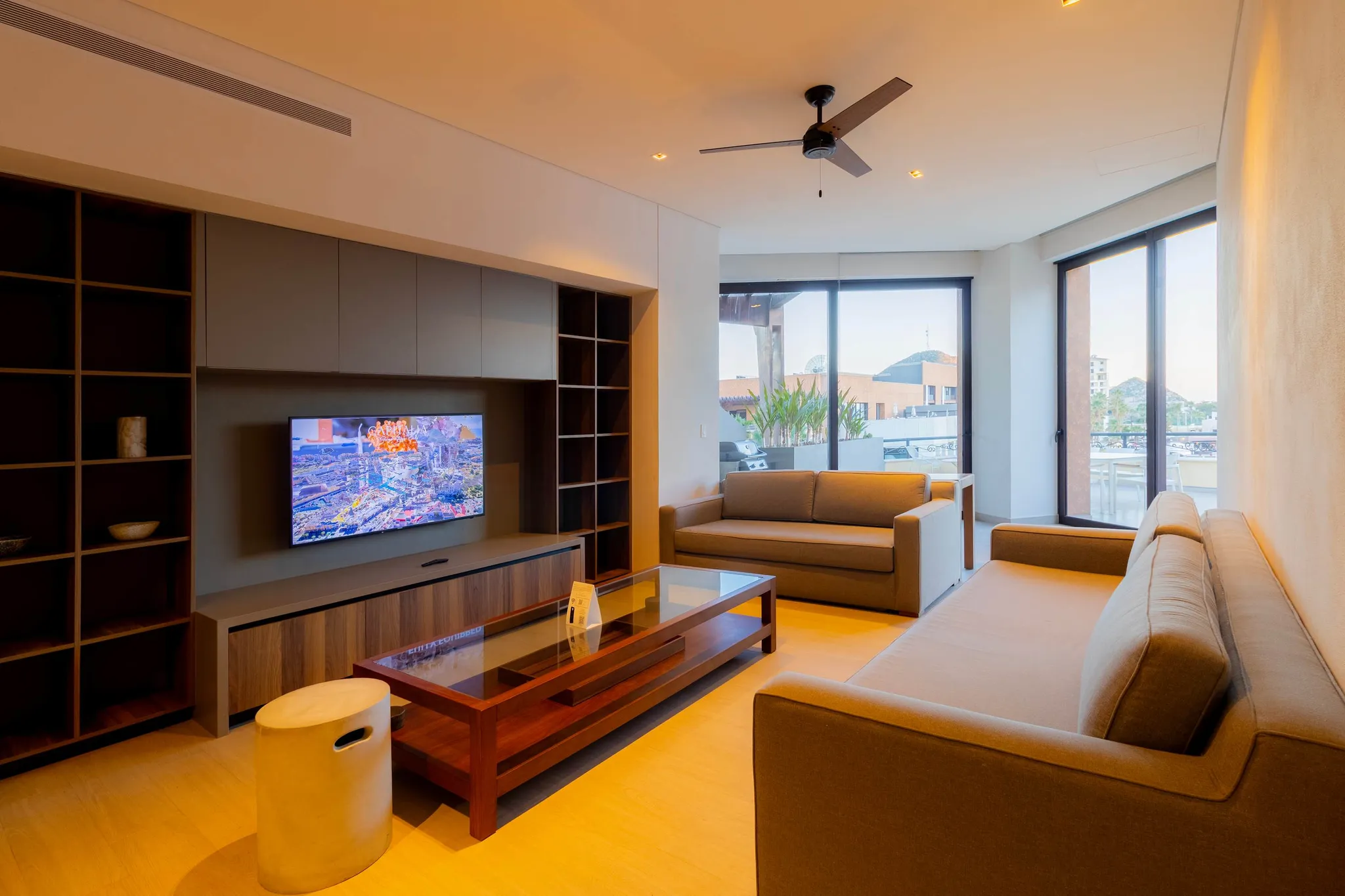 Modern living room with sofas, coffee table, TV, and large windows.