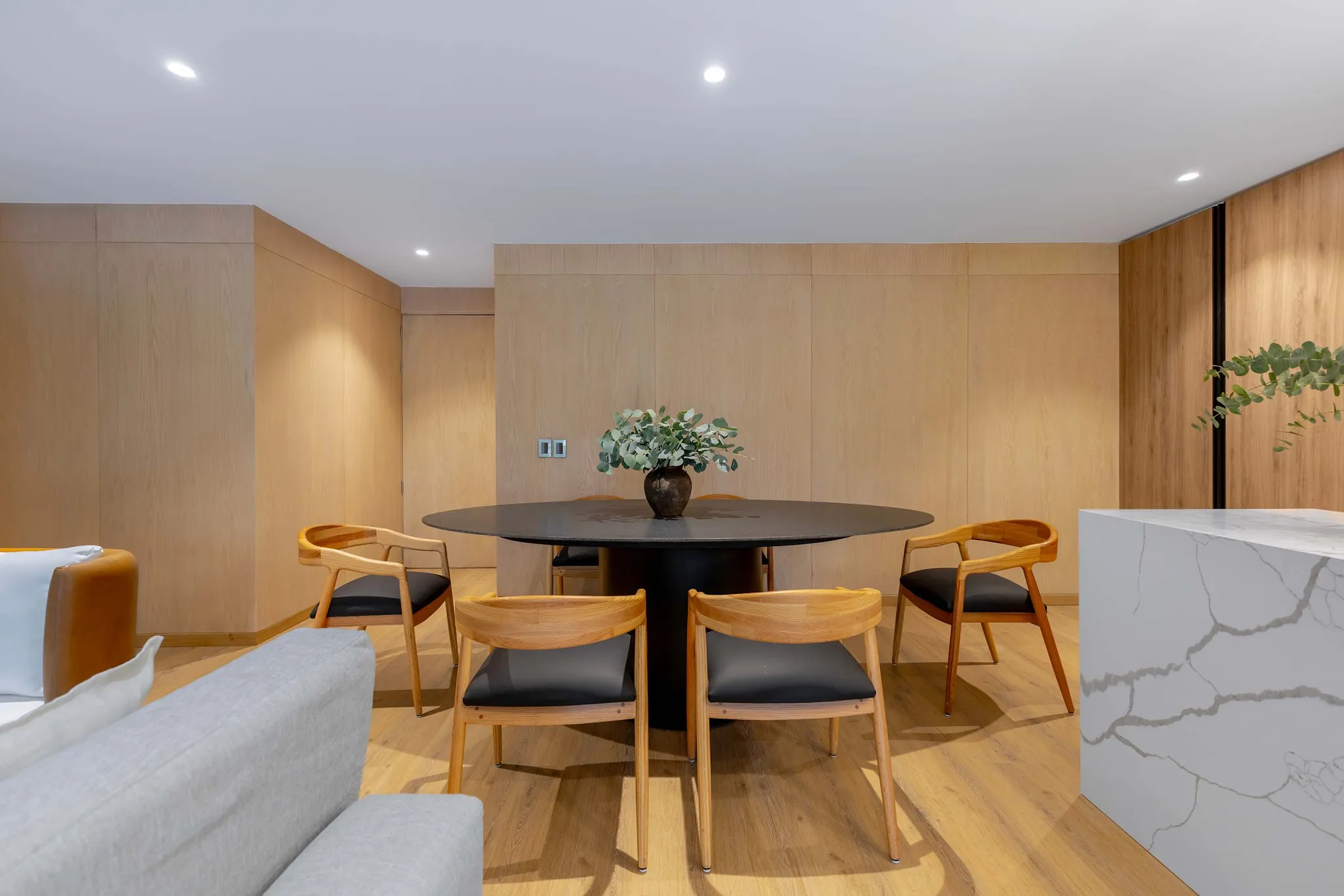 A round dining table with chairs sits in a room with wood-paneled walls.