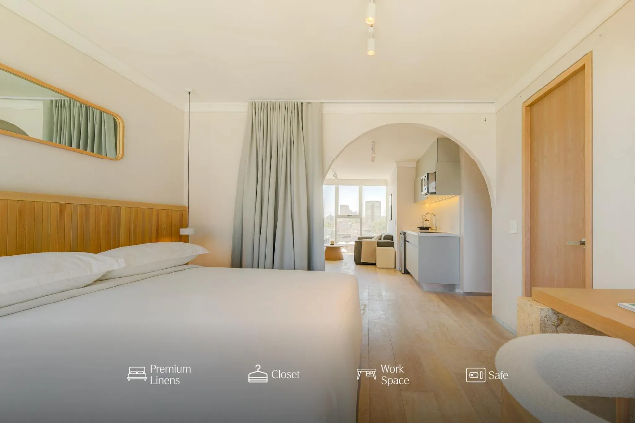 Bright and airy studio apartment with a king bed, kitchenette, and workspace.