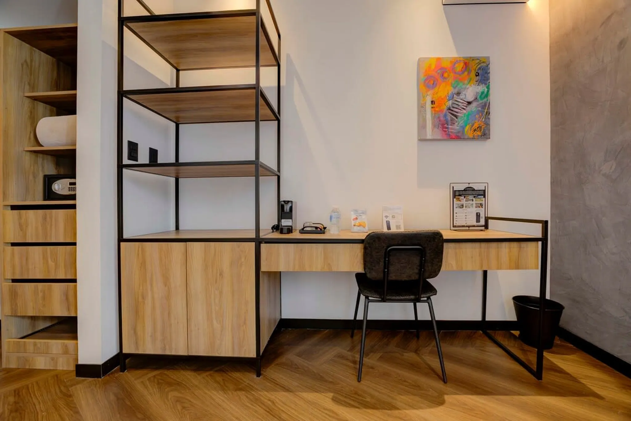 A modern room with a desk, chair, shelves, and a safe.